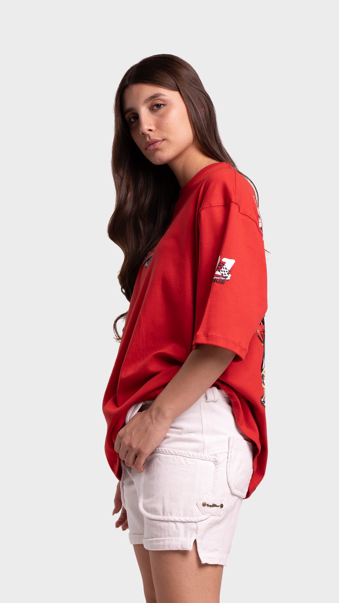 Side profile of a woman wearing a red loose-fit graphic t-shirt showing sleeve print details.