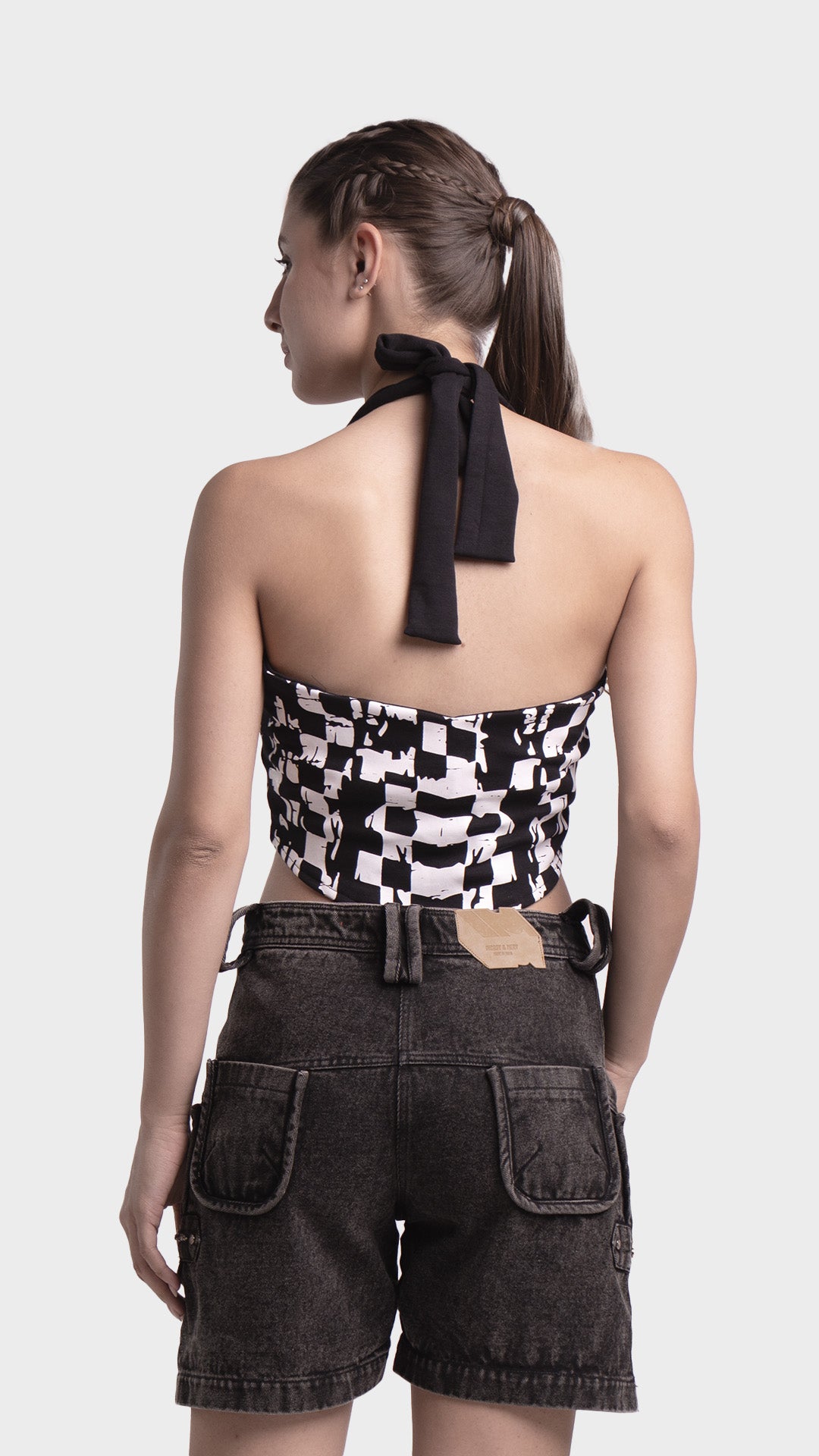 Back view of halter tie-up crop top styled with denim cargo shorts.