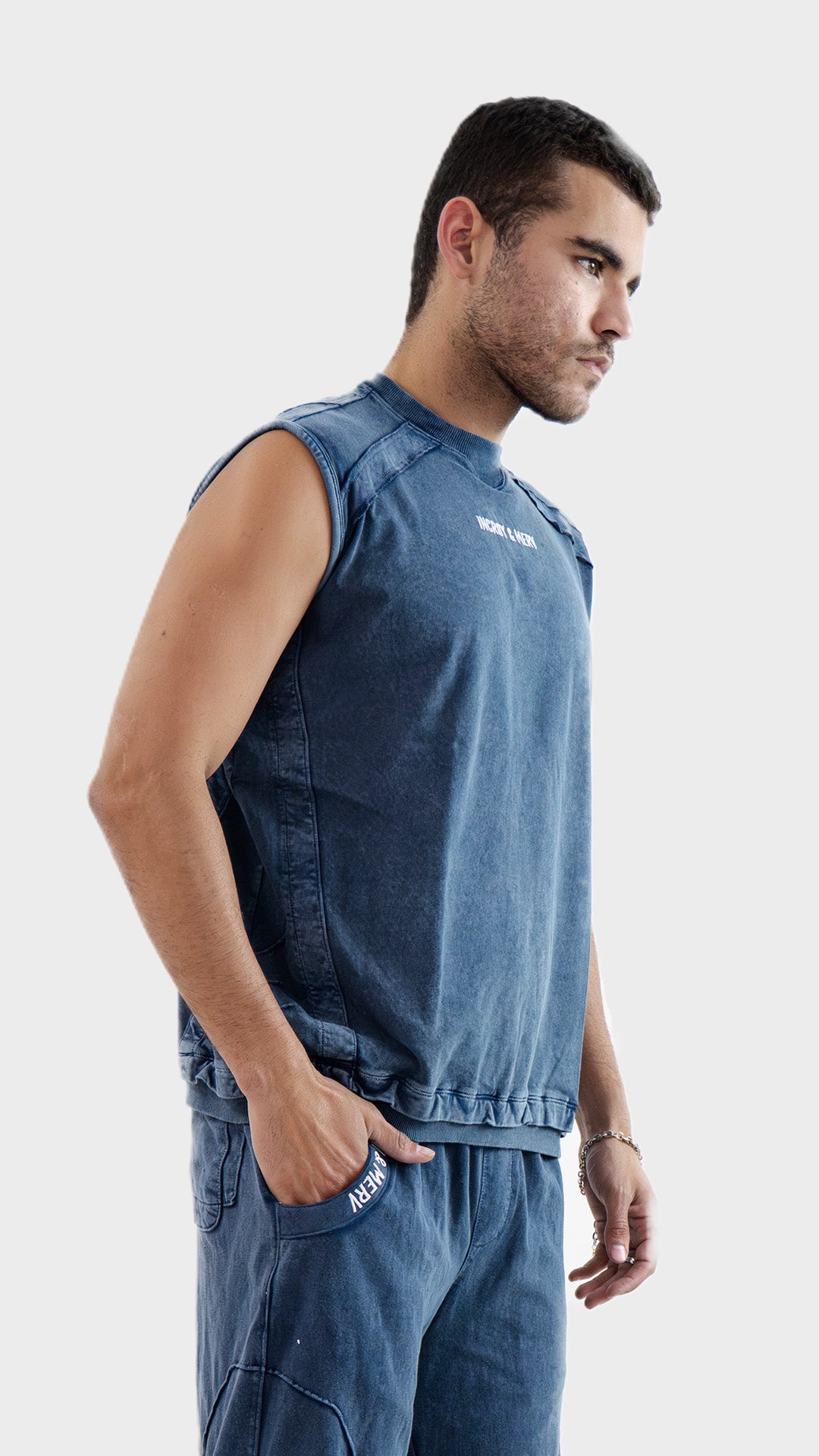 Profile side view of the Incroy and Merv Beyond Tank Top in Dusky Blue showcasing sleeveless streetwear styling.