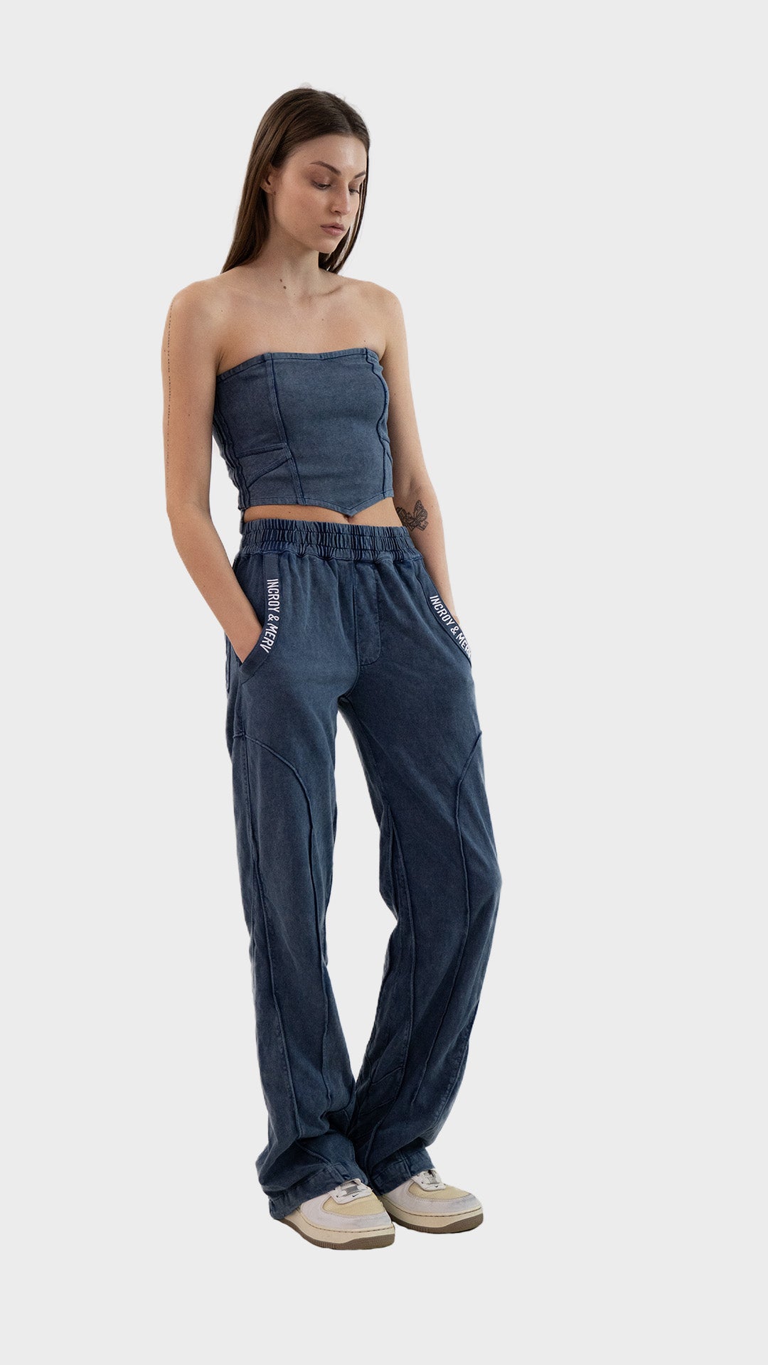 Full length view of model with hands in pockets wearing the Incroy & Merv dusky blue Beyond Tube Top and pants set.