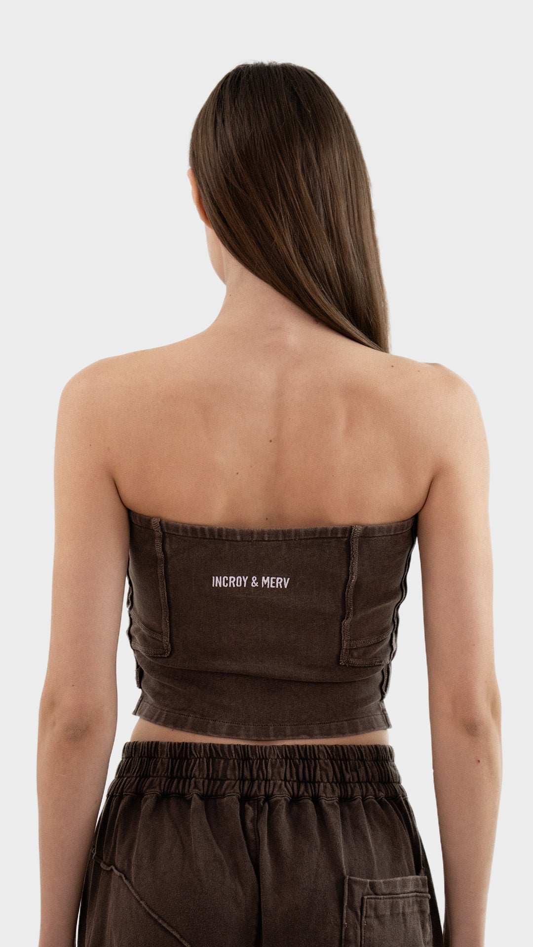Back view of Incroy & Merv women's Beyond Tube Top in brown ribbed fabric showing rear embroidered logo detail.