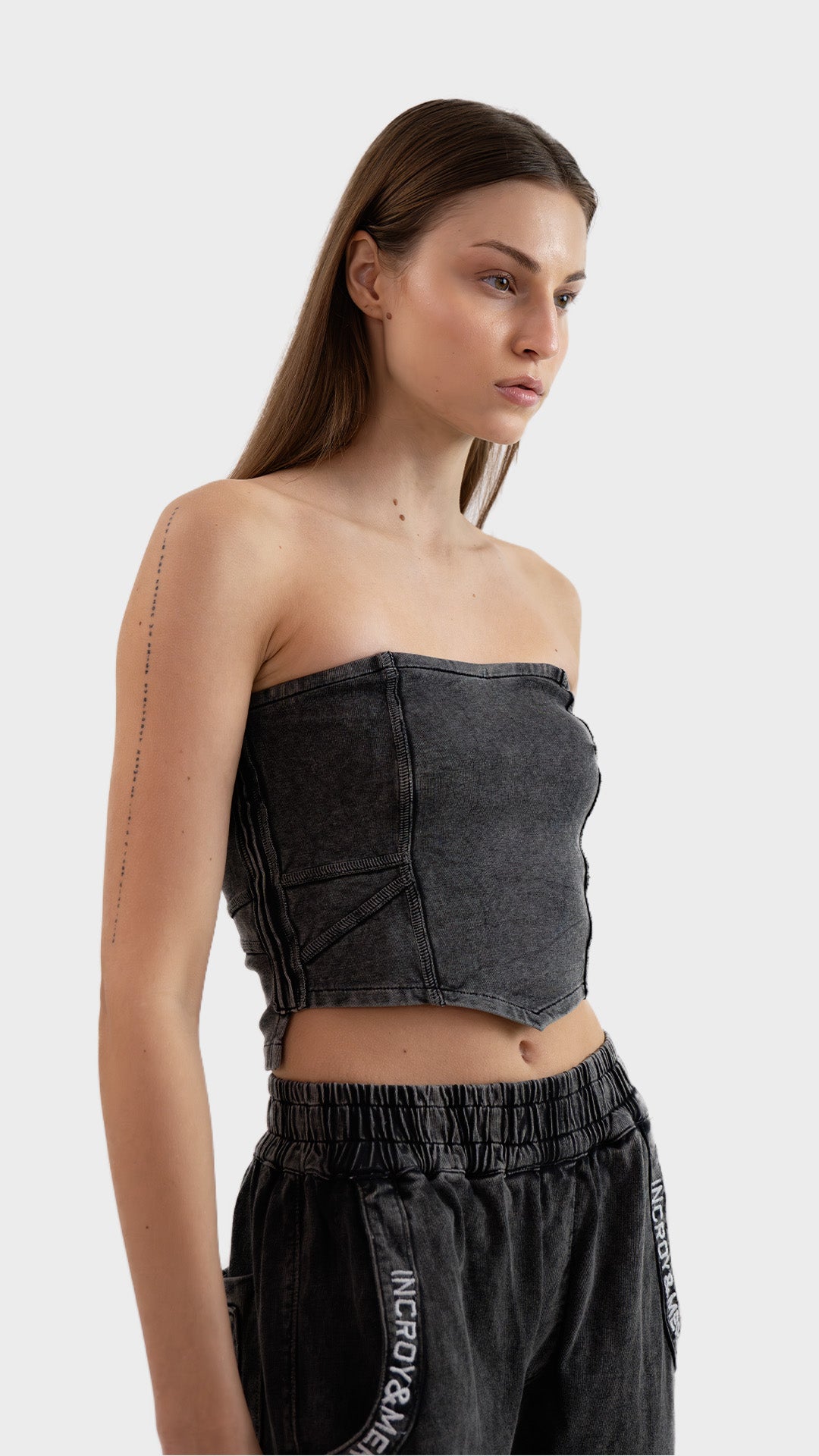 Three-quarter front angle view of a model posing in the washed charcoal Beyond Tube Top in ribbed fabric.