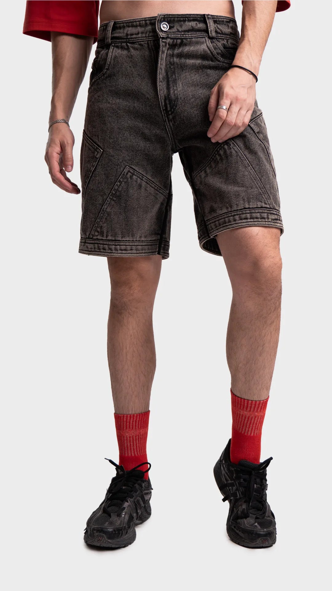 Front styling view of dark grey acid wash denim shorts with red socks.