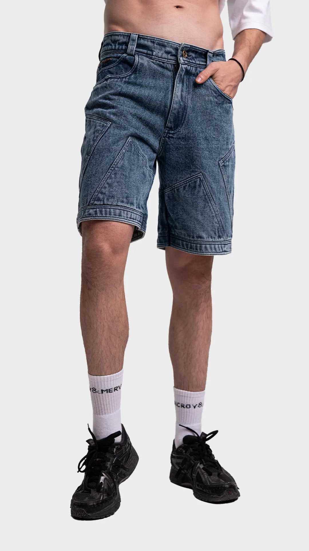 Angled fit view of men's blue acid wash shorts styled with black sneakers.