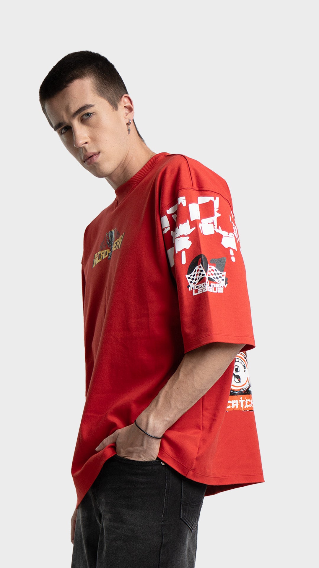 Oversized graphic t-shirt in red. Side profile view of relaxed fit streetwear tee styled with washed black jeans.