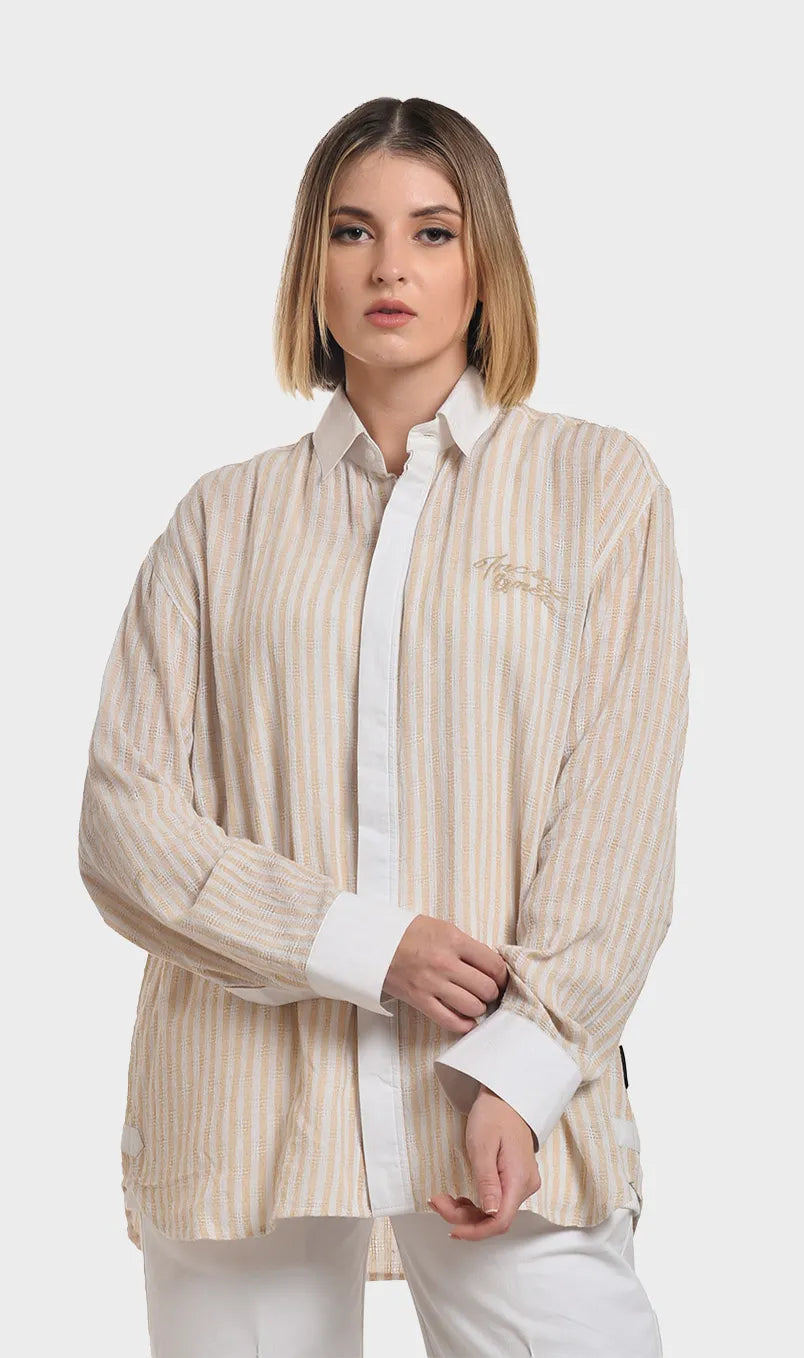 Three-quarter front view of a model in a beige striped dobby fabric shirt featuring solid white placket detailing and buttoned cuffs.