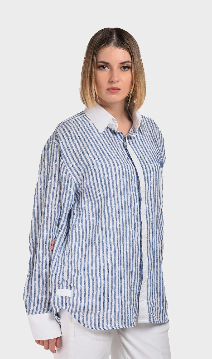 Three-quarter side angle showing the woven dobby fabric pattern and crisp white cuffs on a women's blue striped shirt.