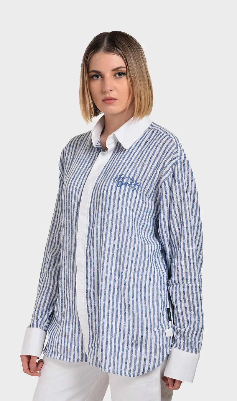 Three-quarter angle of a model wearing a light blue striped dobby button-down shirt with white front placket accents.