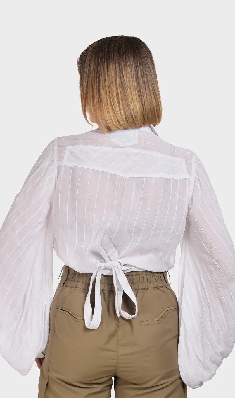 Back view of a white rayon balloon sleeve blouse highlighting the adjustable tie-back waist design and sheer striped texture.