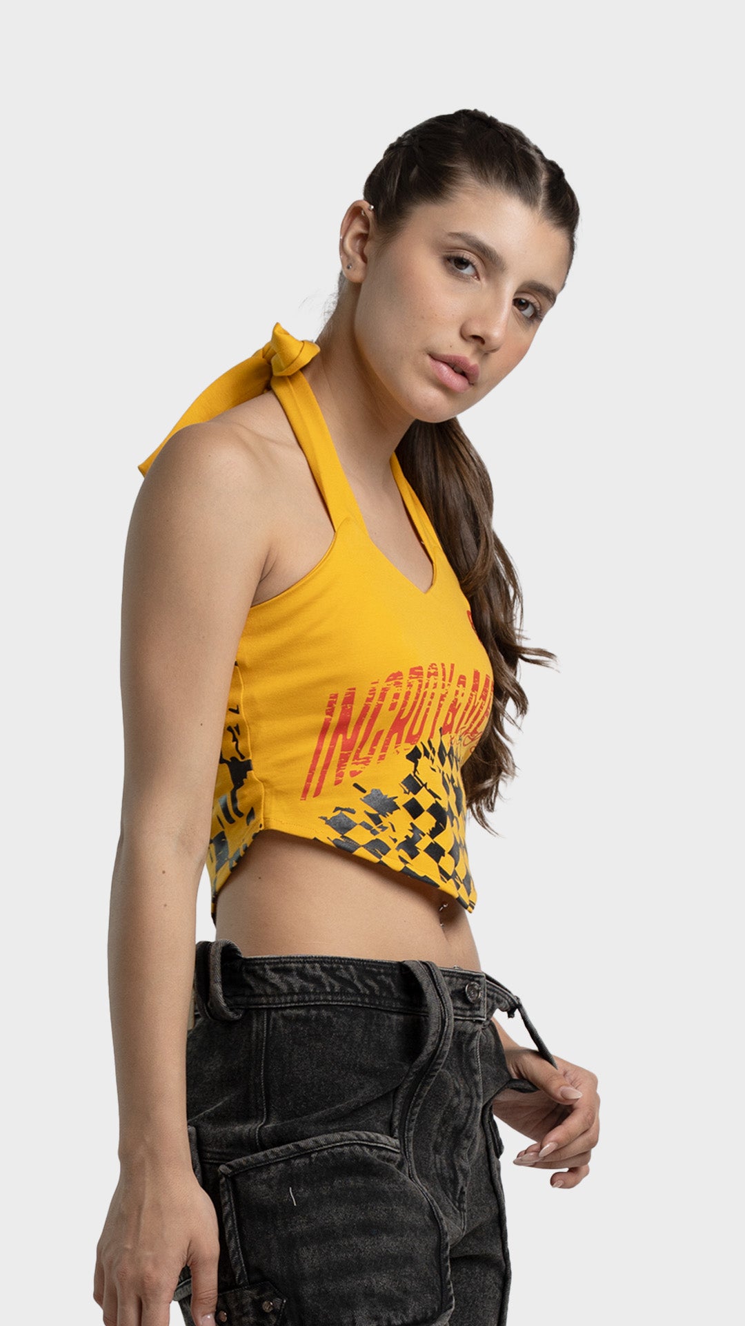 Side view of yellow halter crop top with checkered print and denim shorts.