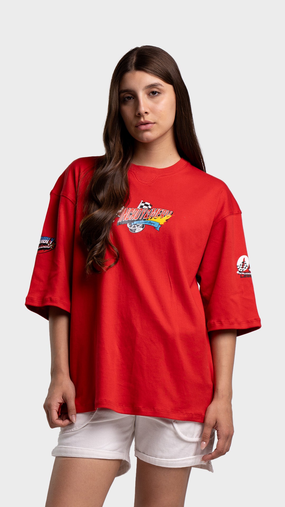 Woman wearing a red oversized streetwear t-shirt with a small retro chest graphic and white shorts.