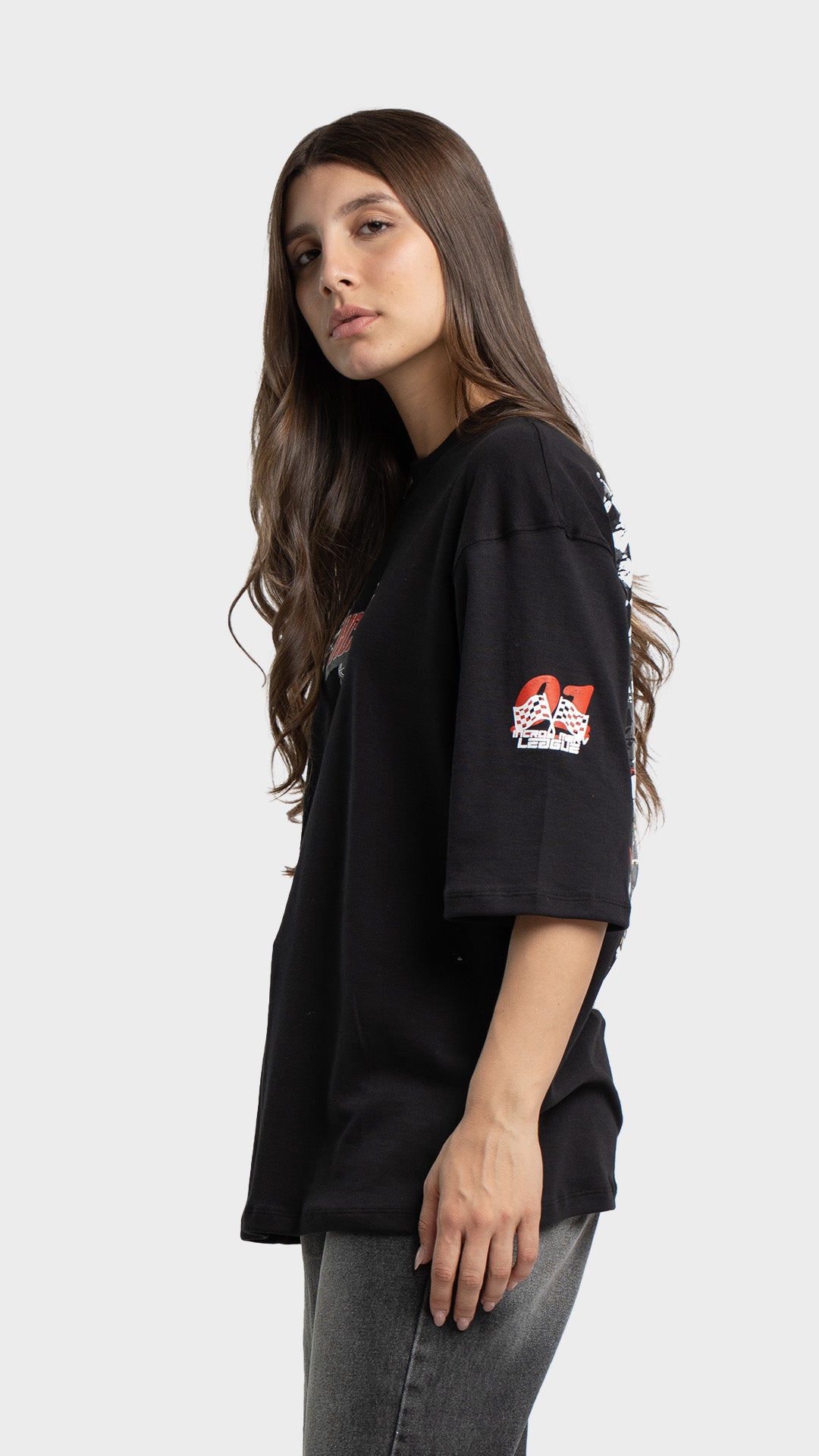 Side profile of a woman wearing a black loose-fit graphic t-shirt showing sleeve print details.
