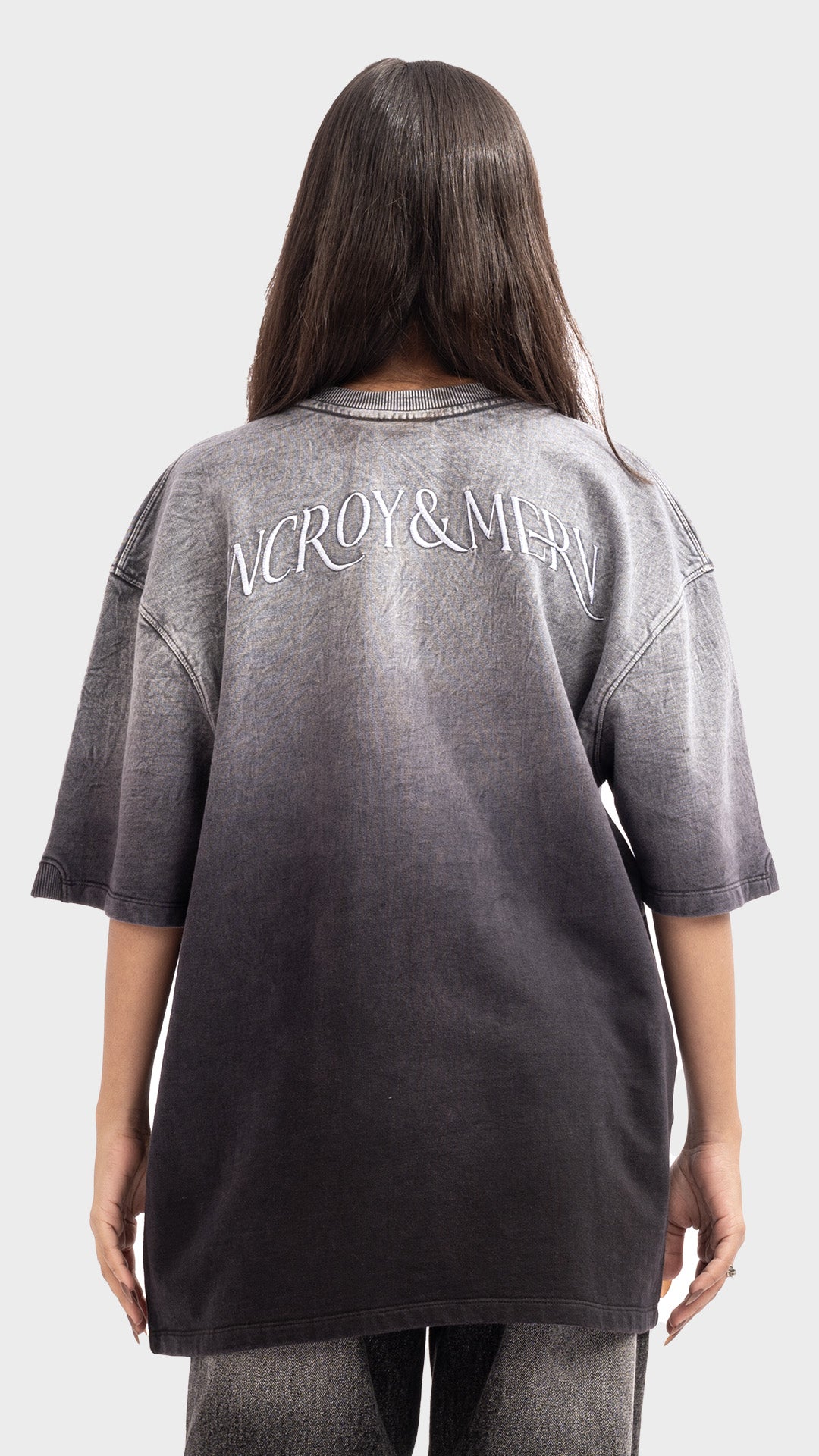 Back view of an oversized acid wash grey ombre t-shirt with white text across shoulders.