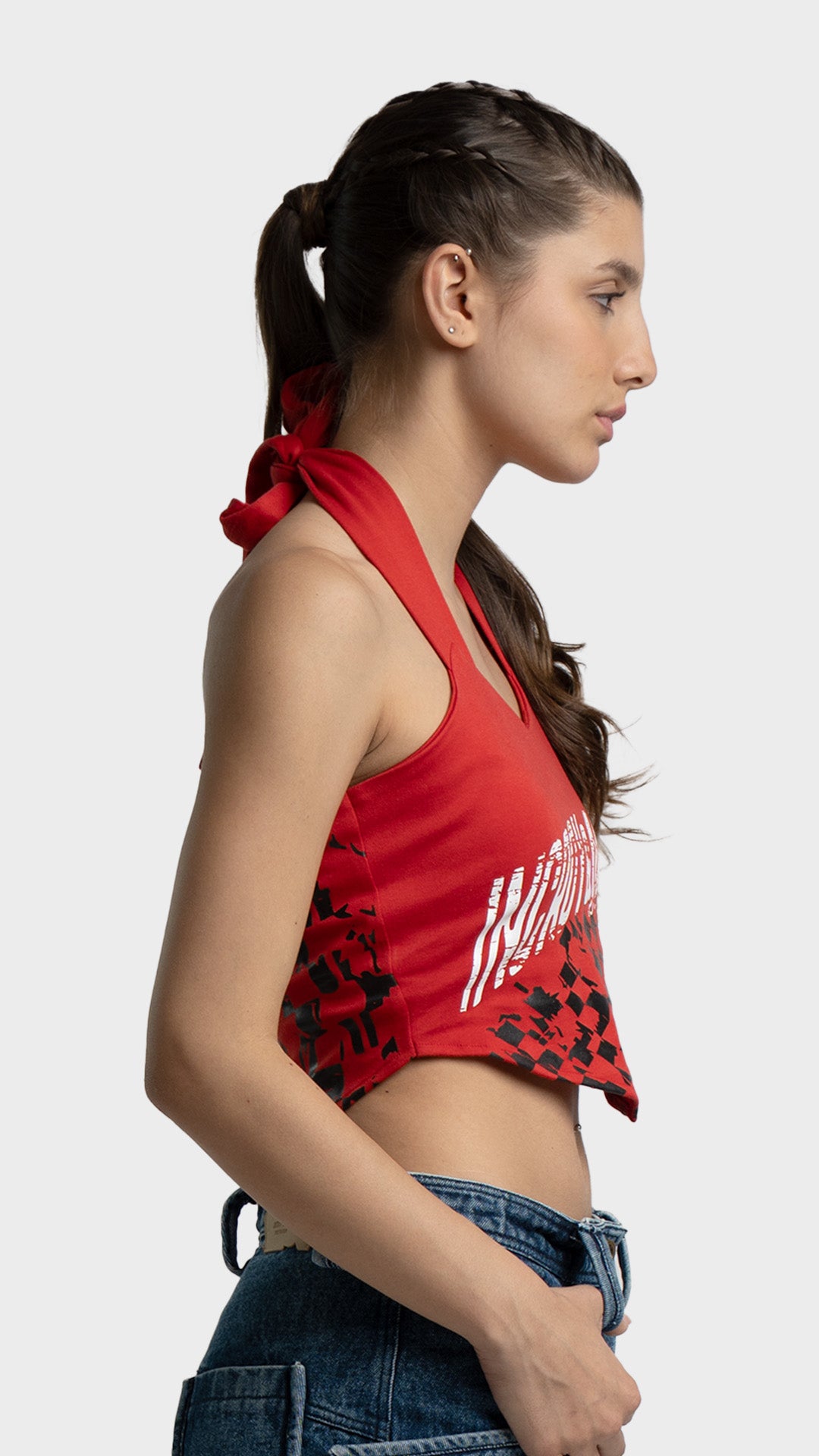 Side profile view of a women's red halter crop top with an asymmetrical handkerchief hemline.