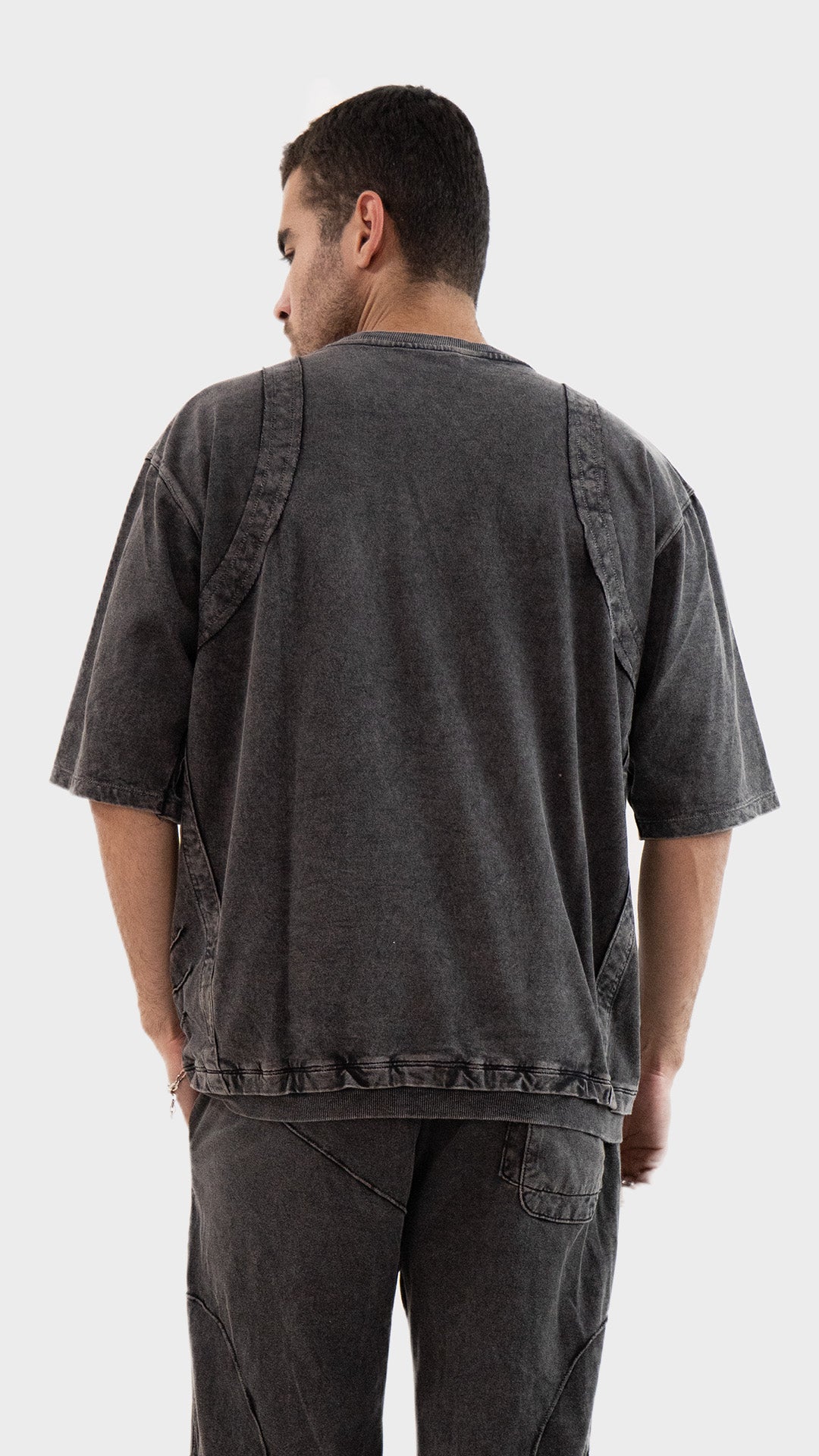 Back view of the Incroy and Merv Charcoal Beyond T-Shirt showing a vintage wash finish and exposed seam stitching.