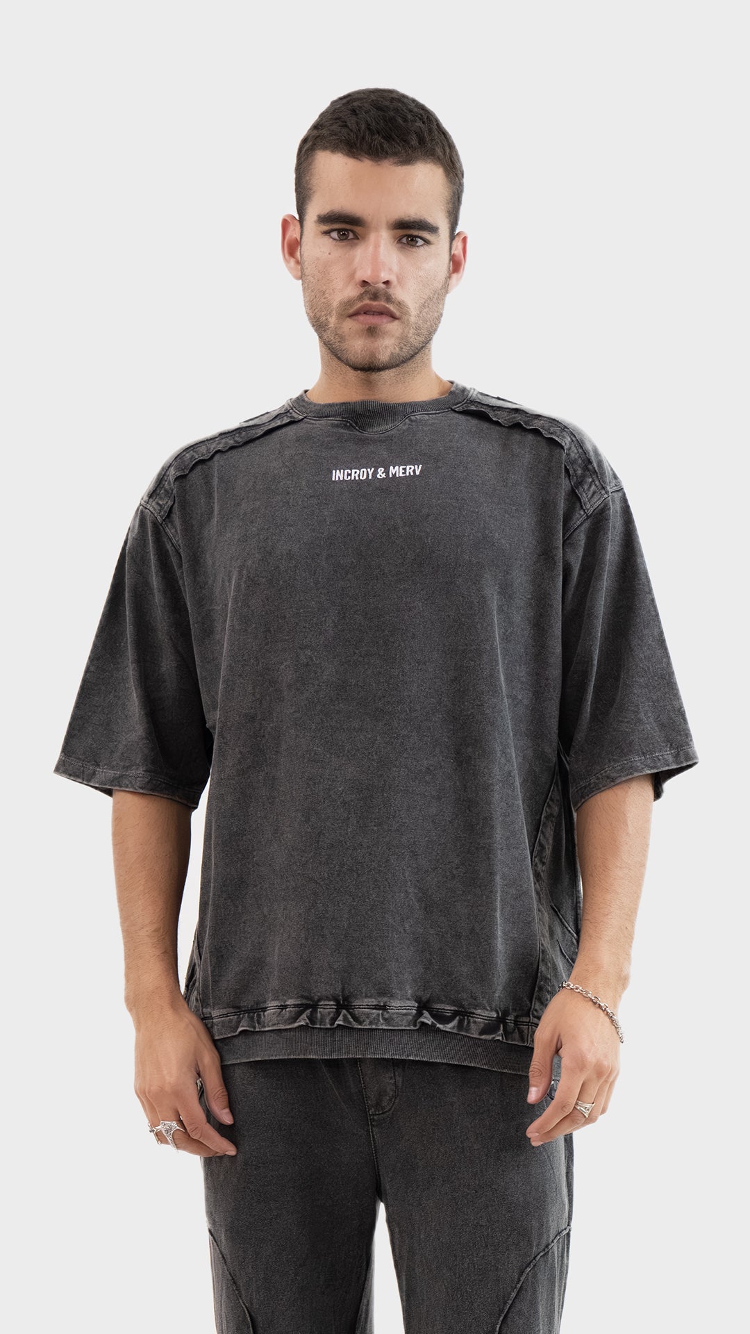 Front view of a man wearing the Incroy and Merv Beyond T-Shirt in Charcoal featuring an oversized fit and chest logo.