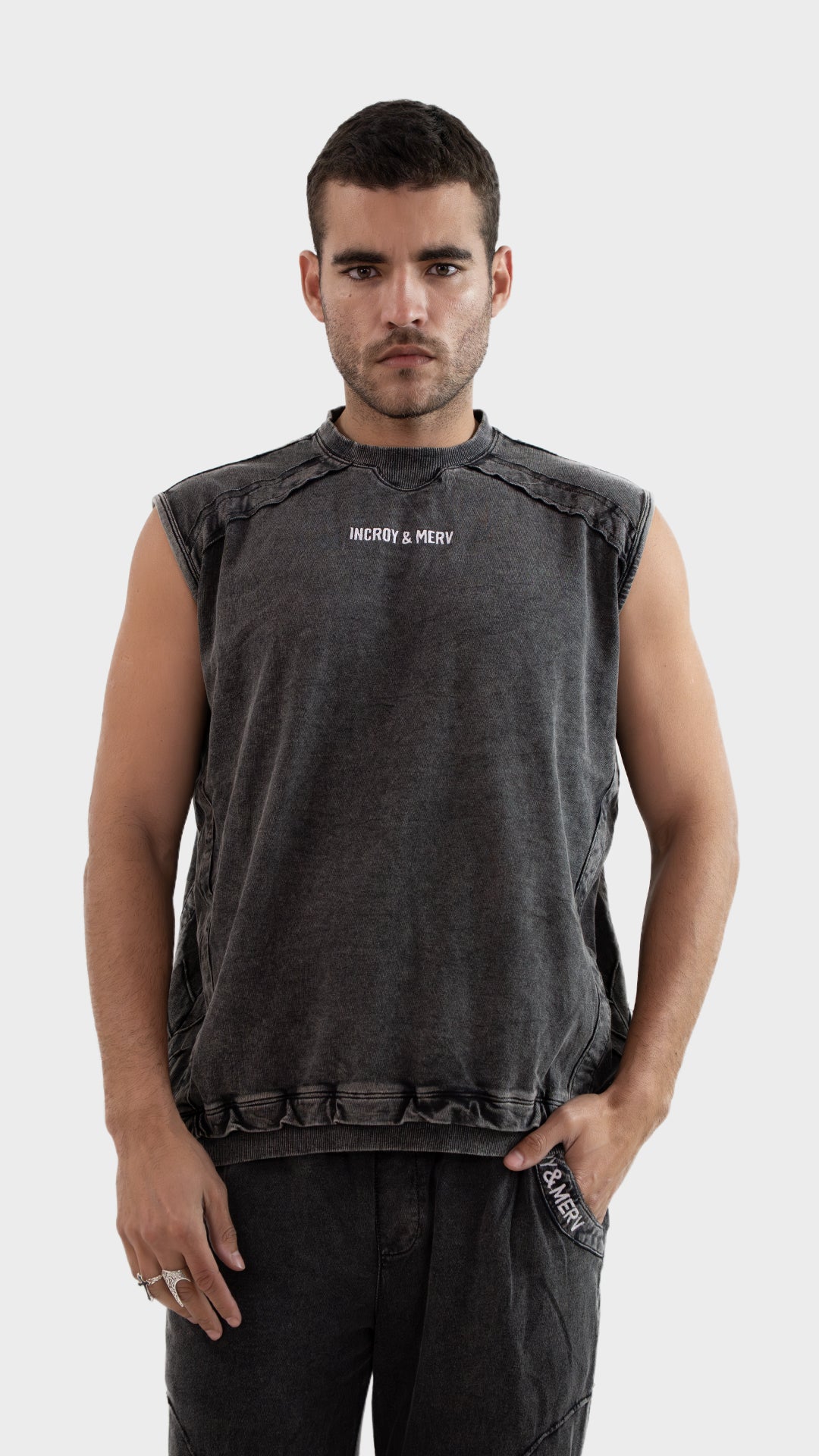 Front view of a male model wearing the Incroy and Merv Beyond Tank Top in Charcoal made from sinker cotton fabric with chest logo.