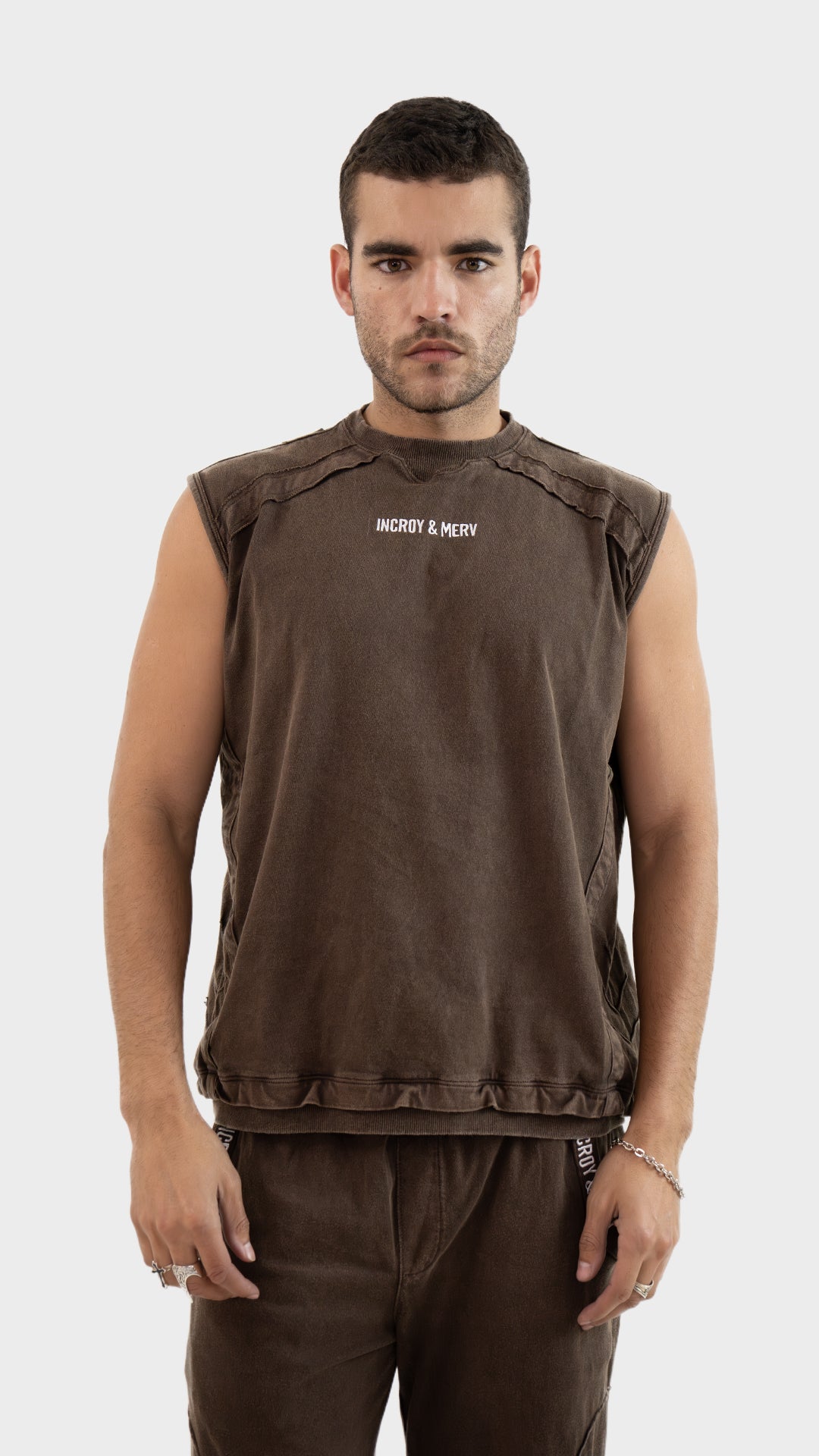 Front view of a male model wearing the Incroy and Merv Beyond Tank Top in Rustic Brown made from sinker cotton fabric with chest logo.