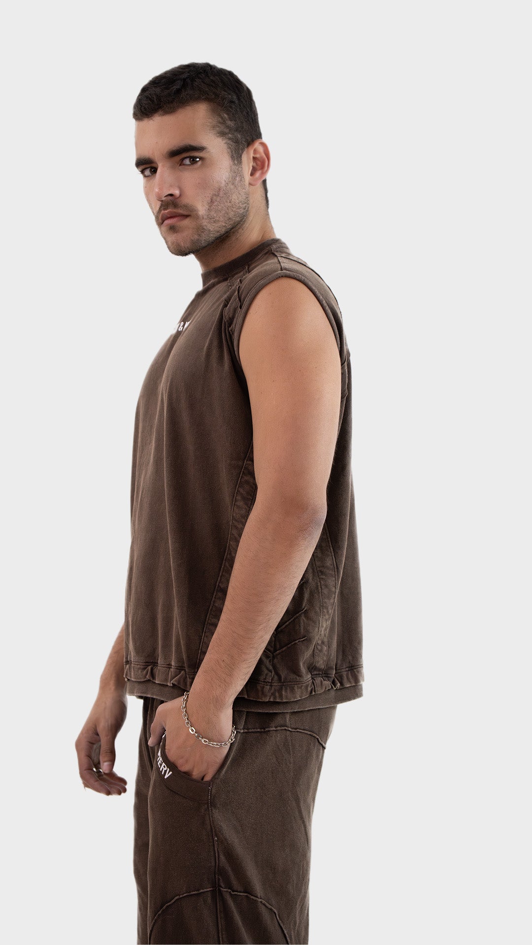 Profile side view of the Incroy and Merv Beyond Tank Top in Rustic Brown showcasing sleeveless streetwear styling.