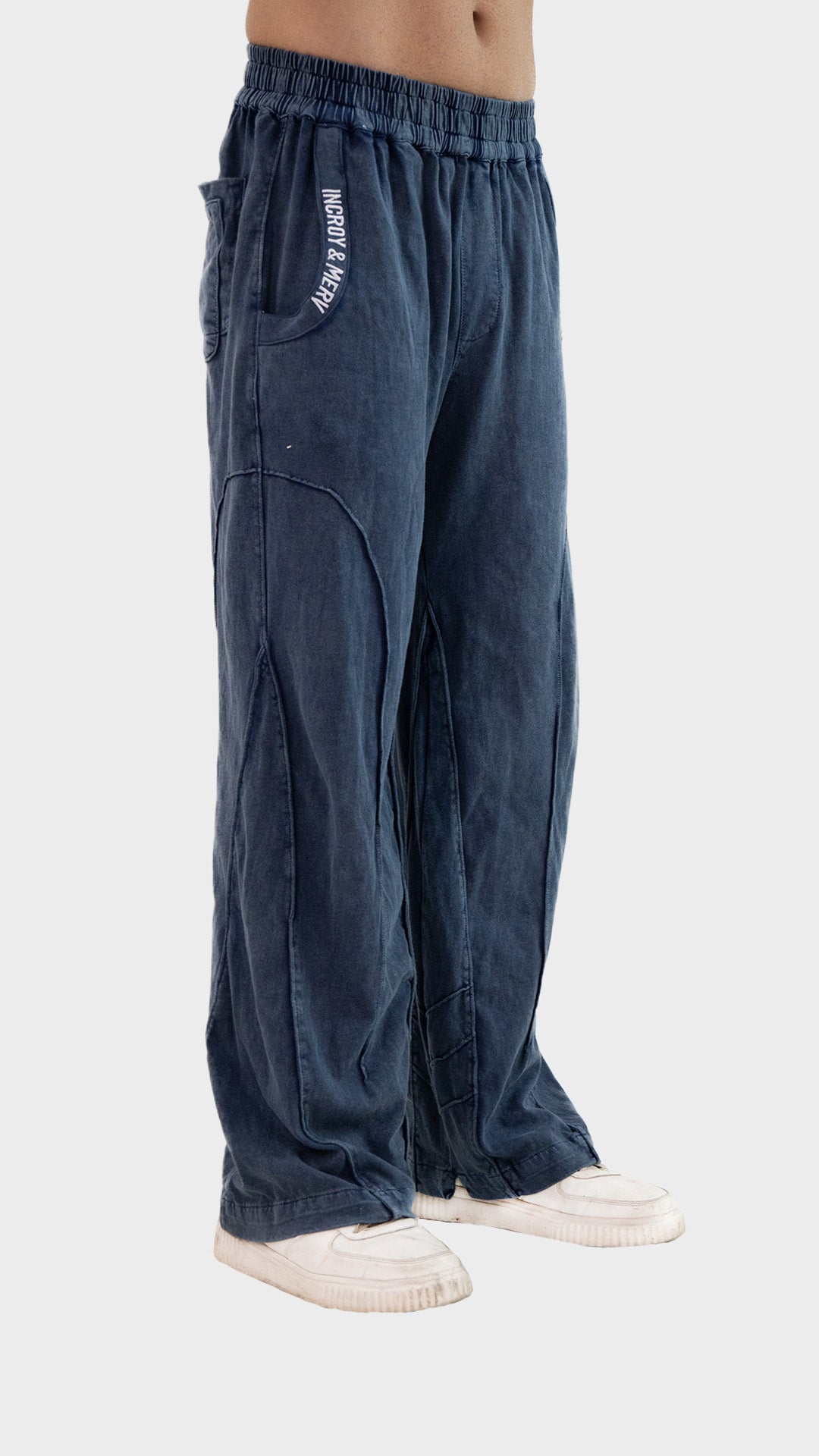 Three-quarter front angle view of Incroy & Merv men's Beyond Trouser in dusky blue showing side pocket embroidery.