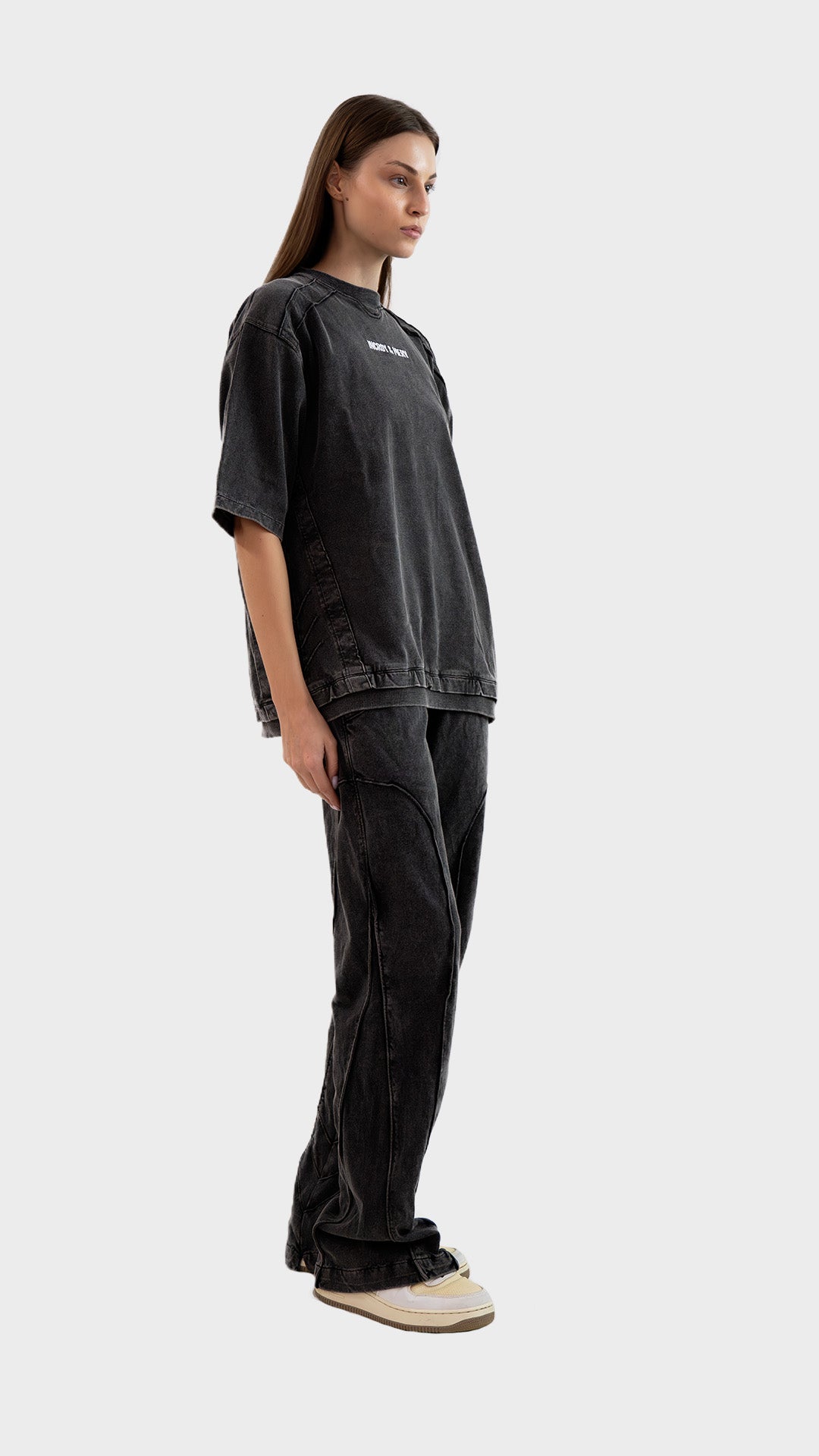 Side profile view showing the relaxed straight fit and raw edge seam design of Incroy & Merv women's charcoal lower.