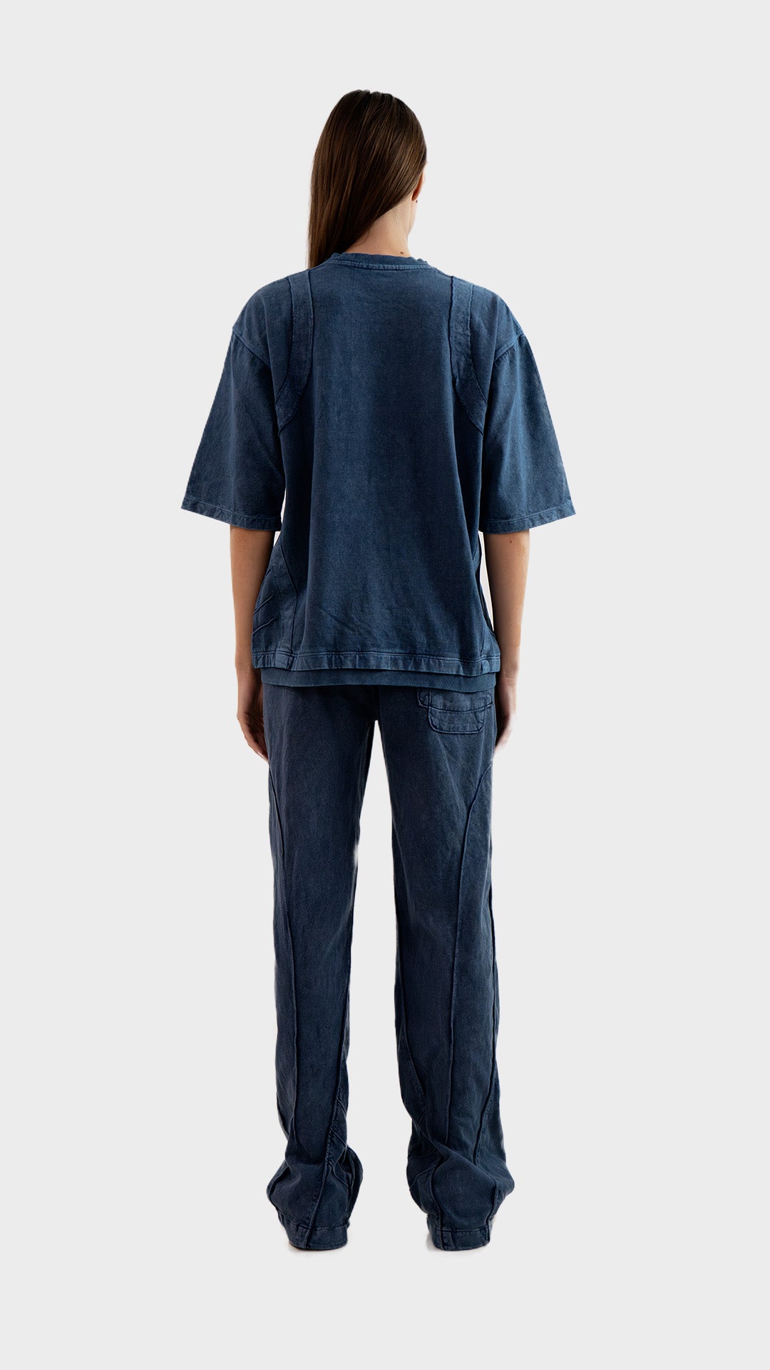 Full length back view of female model wearing Incroy & Merv women's dusky blue Beyond Lower showing rear pocket and seam detailing.