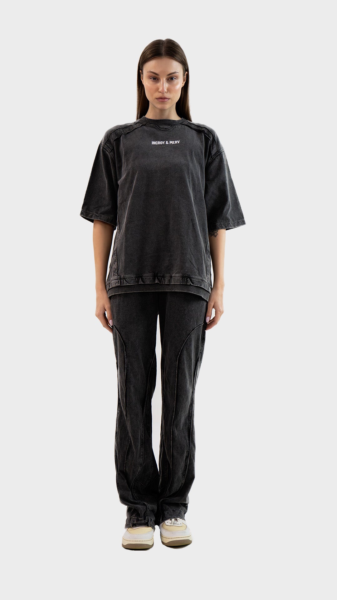 Full body view of a woman wearing the Incroy & Merv Beyond T-Shirt styled with matching charcoal cotton sinker track pants.