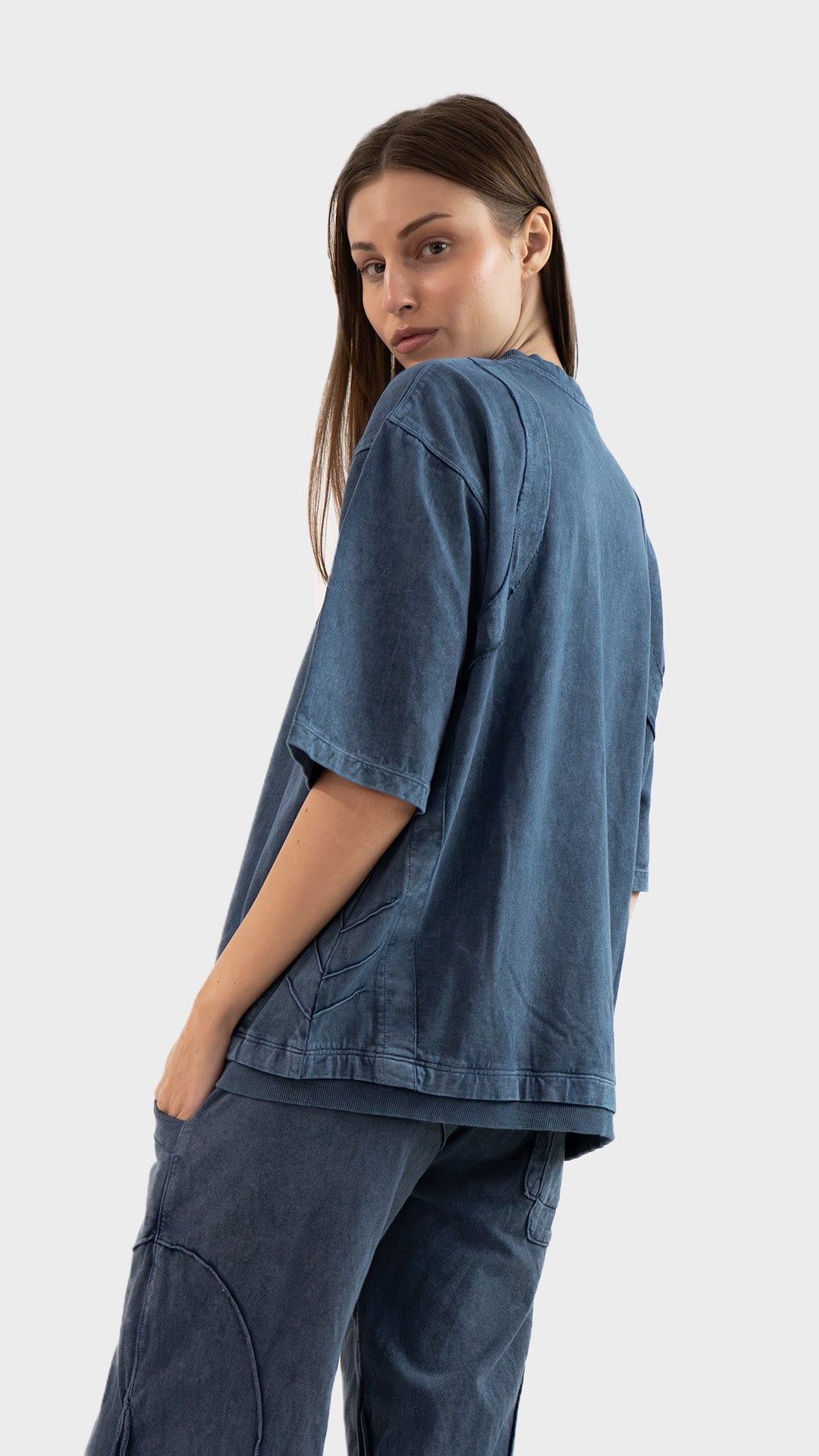 Three-quarter back view of a woman posing in the dusky blue Beyond T-Shirt by Incroy & Merv.
