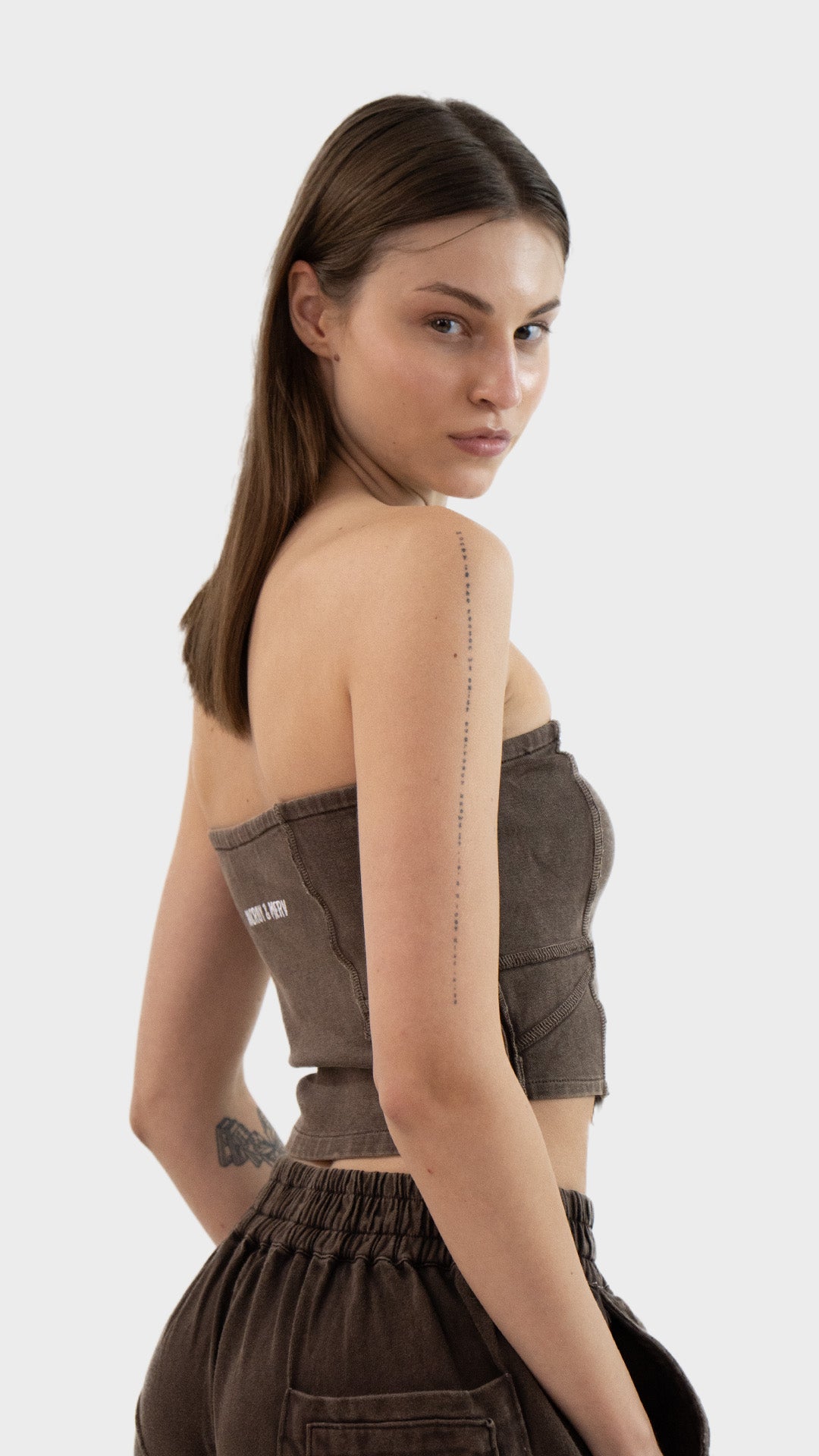 Three-quarter back view of a woman posing in the washed brown Beyond Tube Top in ribbed fabric.