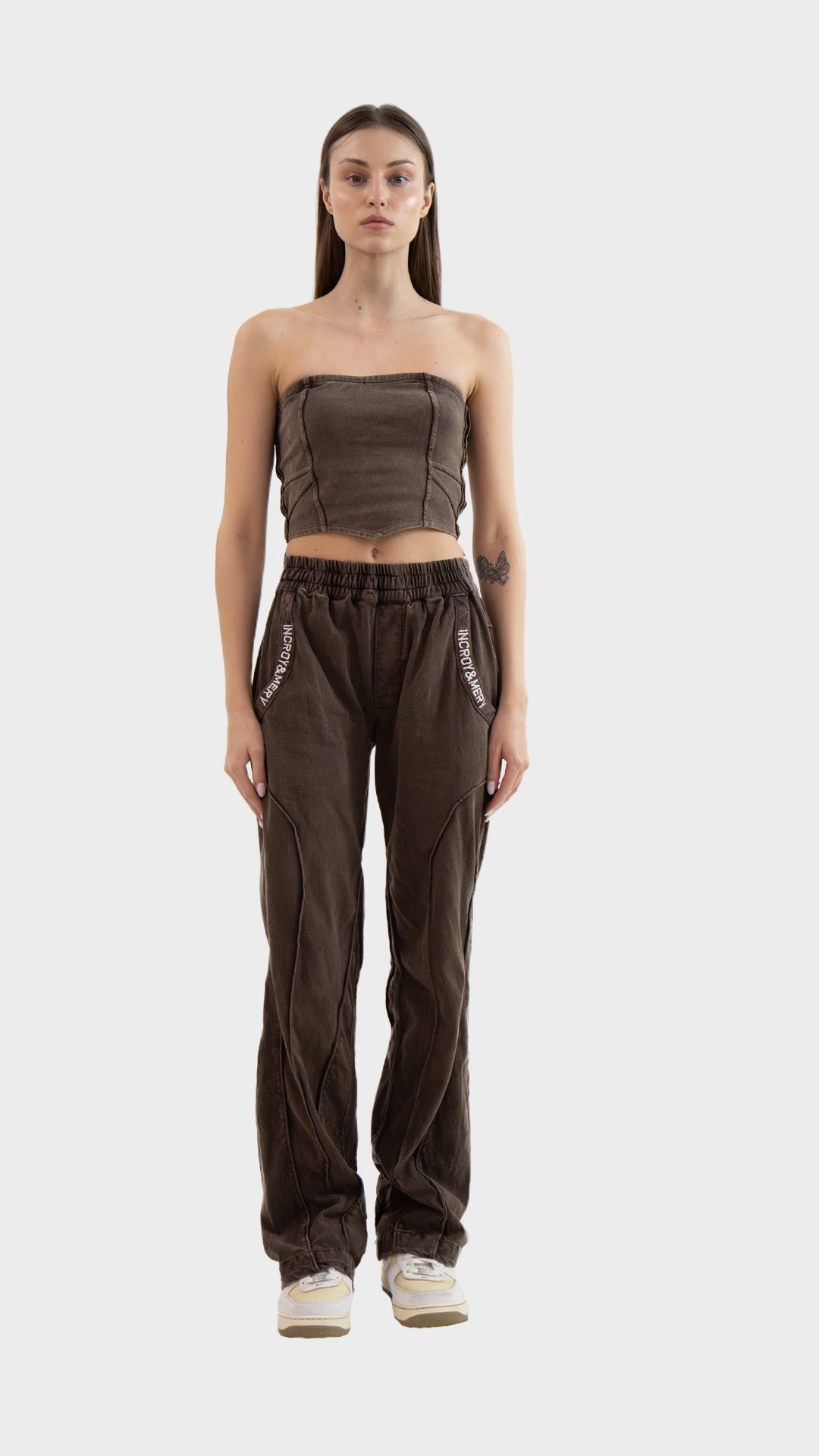 Full length view of a model wearing the Incroy & Merv Beyond Tube Top styled with matching brown track pants.