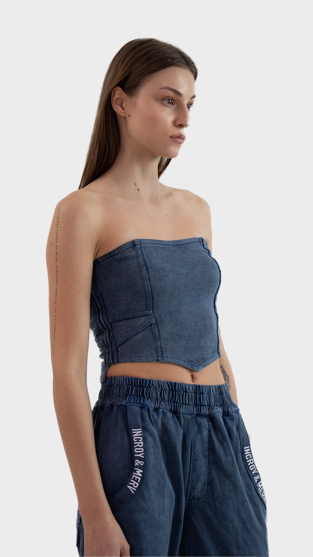 Three-quarter angle view of a woman posing in the dusky blue Beyond Tube Top in ribbed fabric.