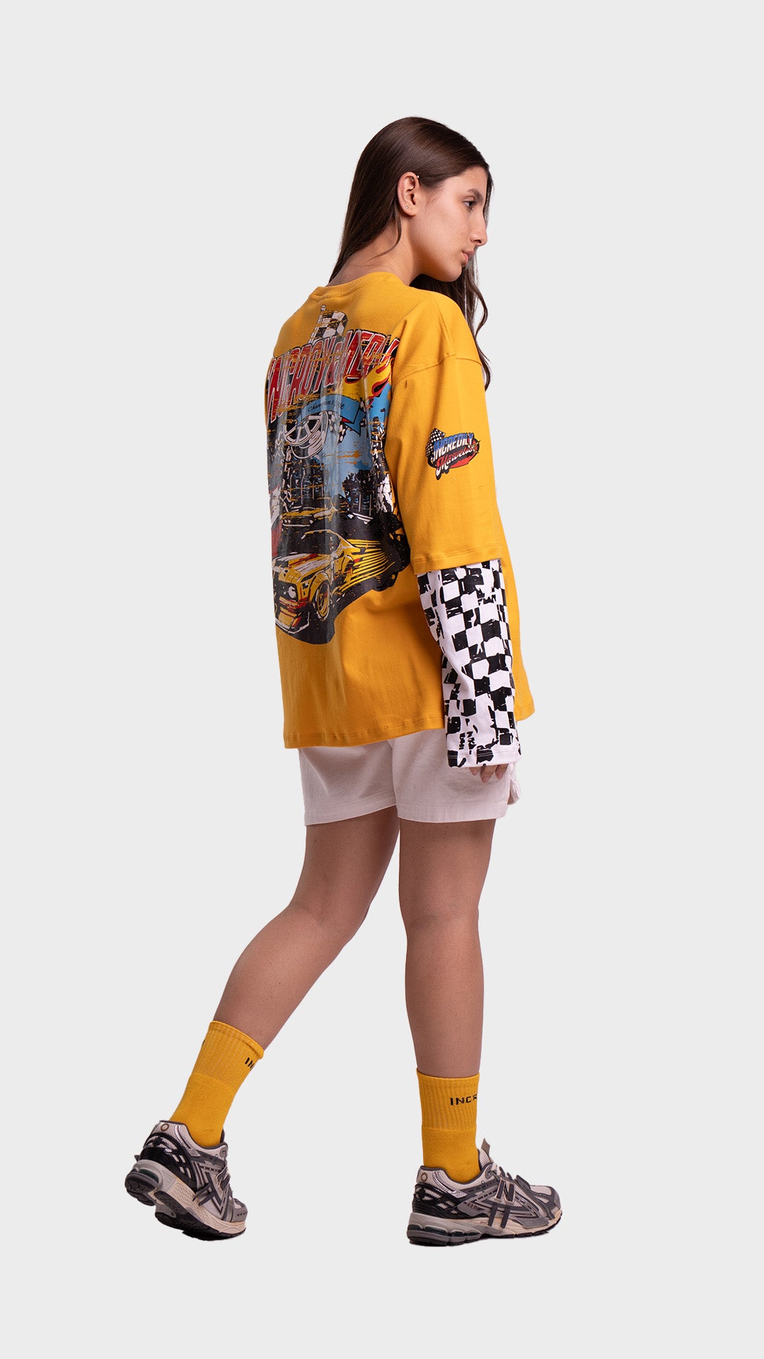 Full body back view of an Incroy & Merv yellow oversized streetwear t-shirt paired with white shorts.