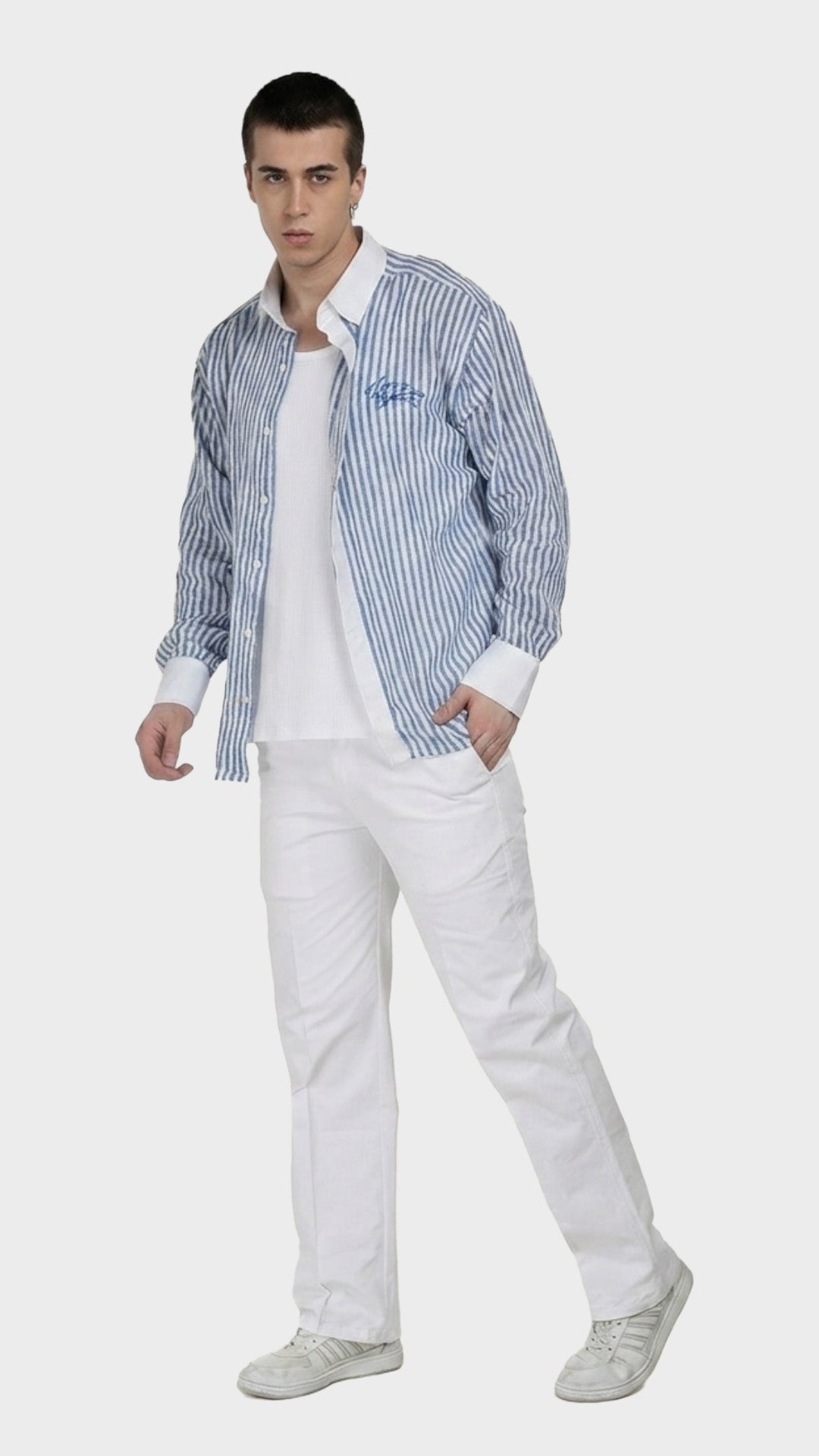 Full-body view of a model in an unbuttoned blue striped dobby shirt and white pants.