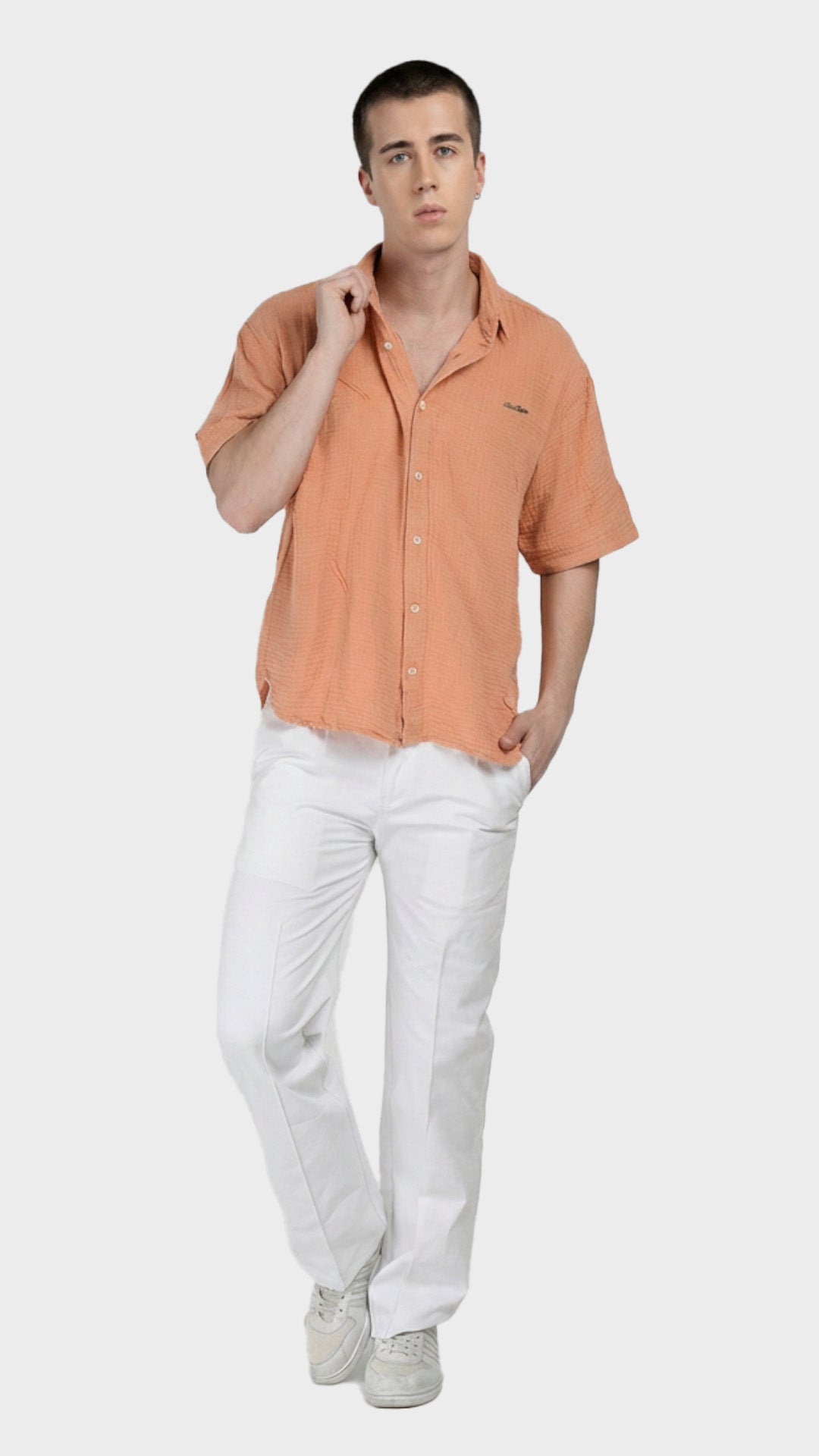 Full-body shot of a male model wearing a peach double cloth cotton shirt with white pants.