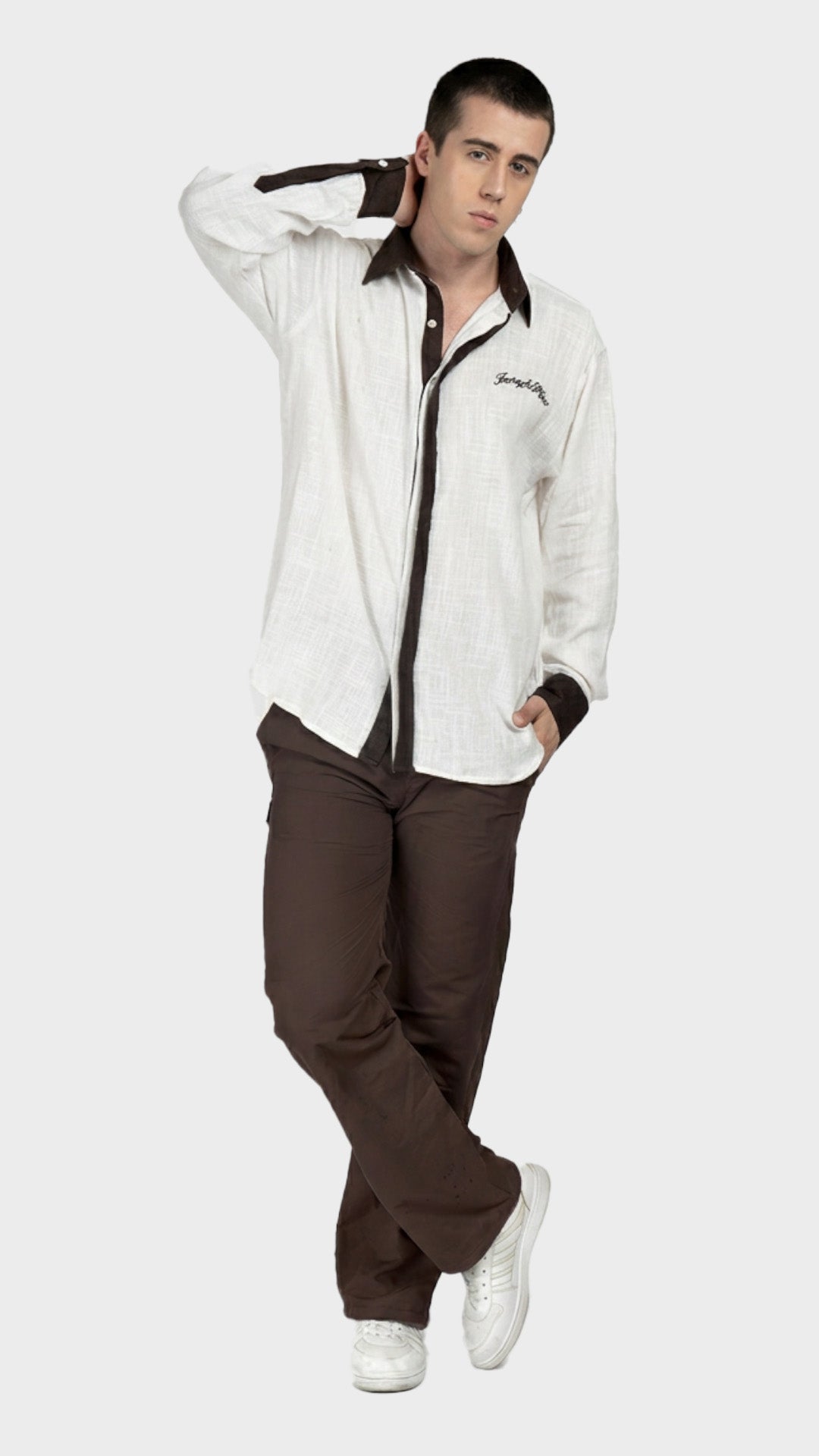Full-body shot of a male model wearing a white slub fabric contrast shirt with brown pants.