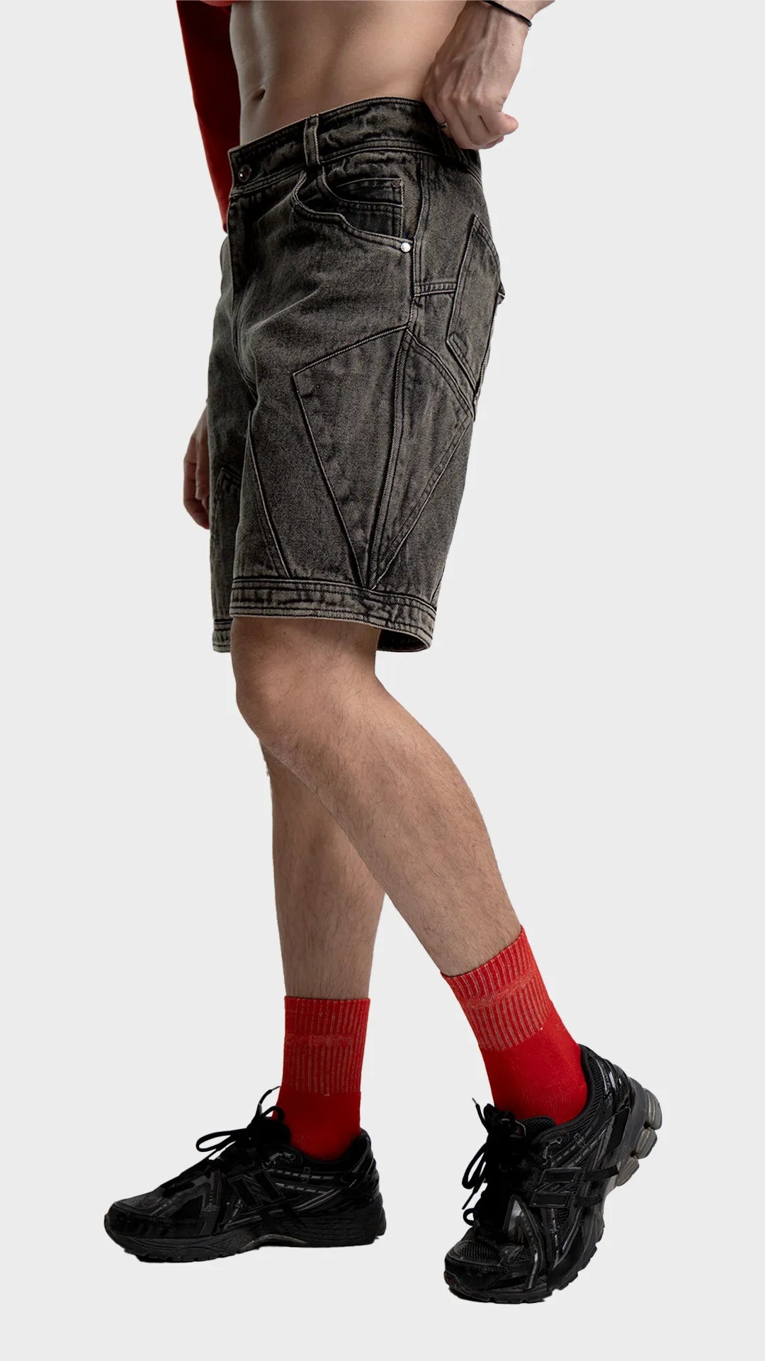 Side view of men's dark grey acid wash jean shorts showing length and panel stitching.