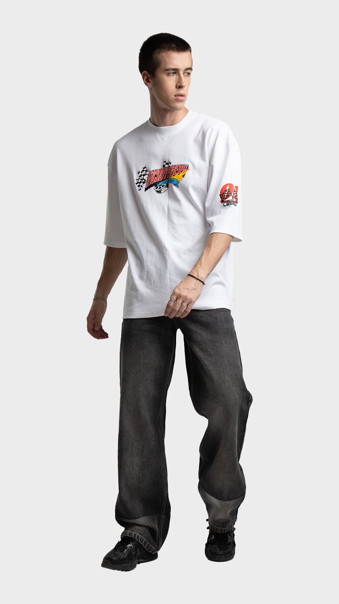 Full body styling of a white oversized graphic t-shirt with dark grey baggy jeans.