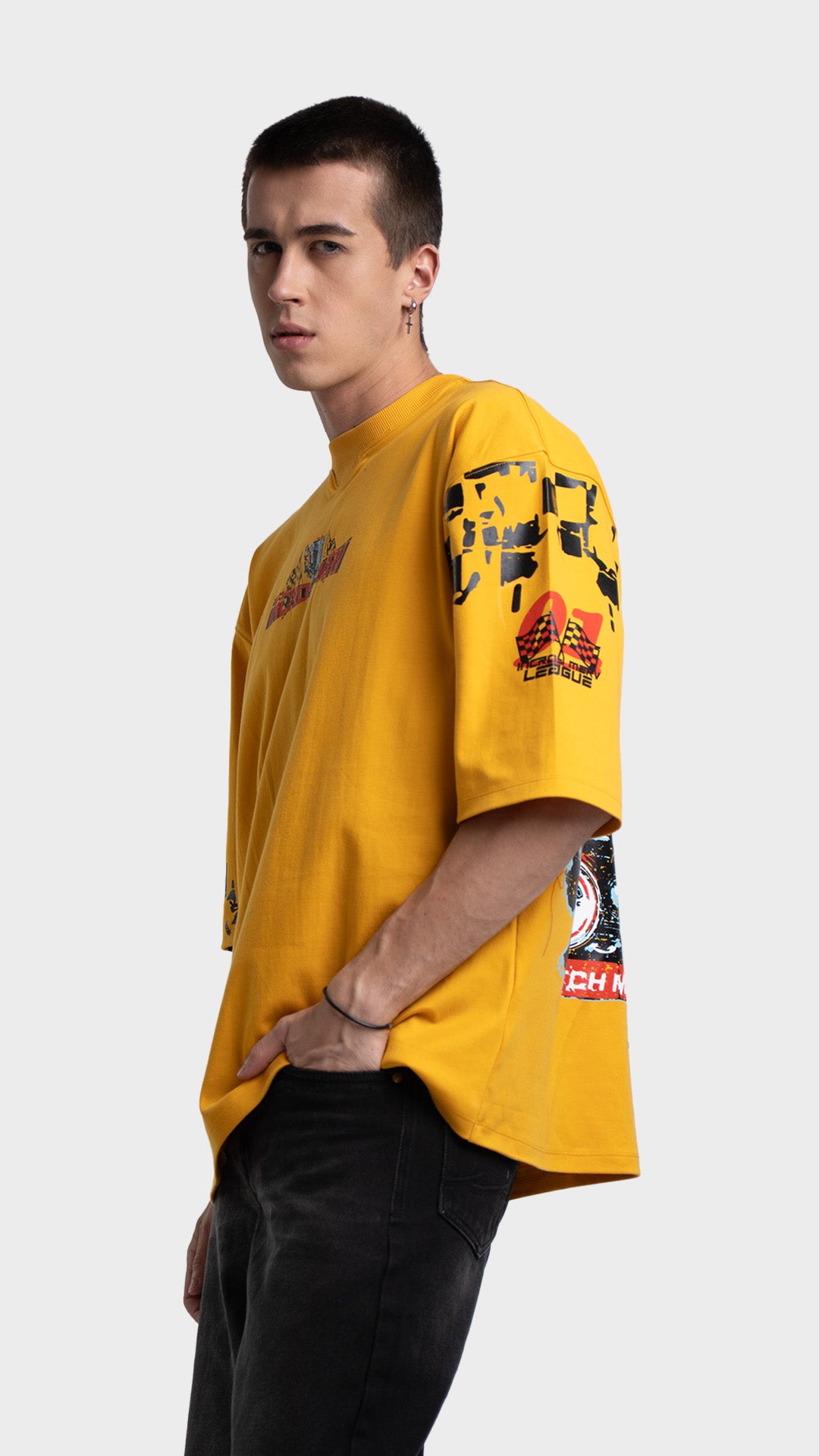 Oversized graphic t-shirt in yellow. Side profile view of relaxed fit streetwear tee paired with faded black jeans.