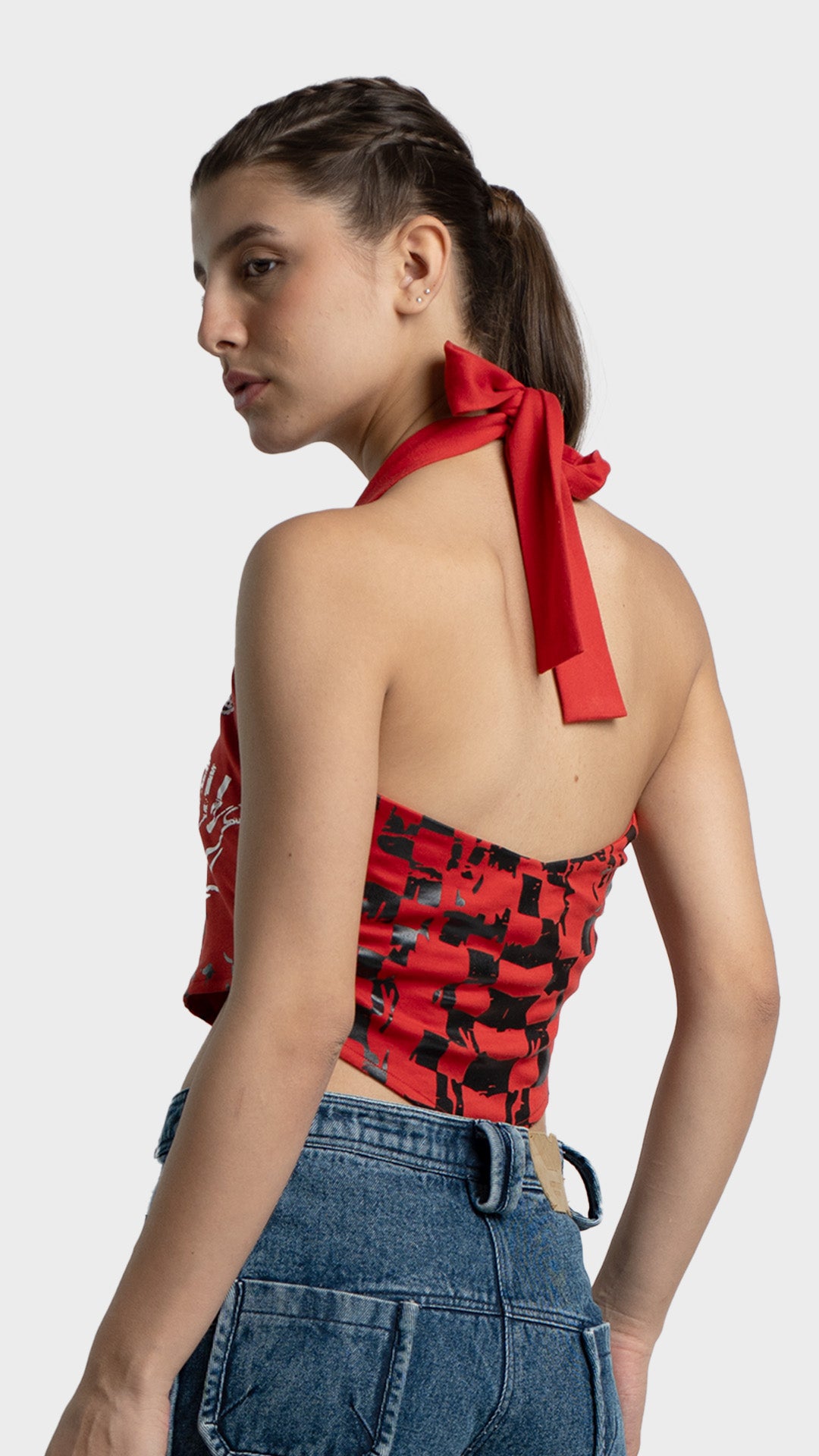 Angled back view of a red graphic halter crop top showcasing the open back and tie neck detail.