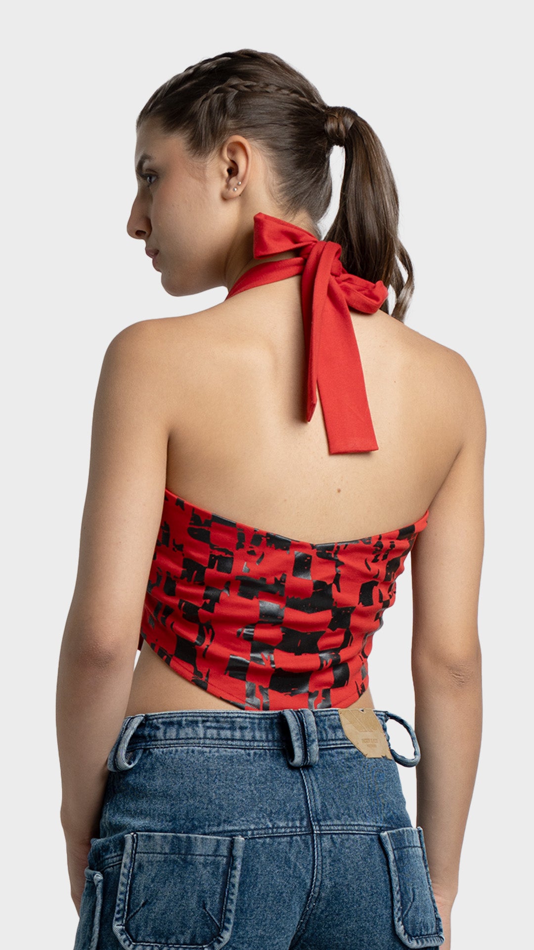 Back view of a red backless halter top with a black checkered flag print and neck tie.