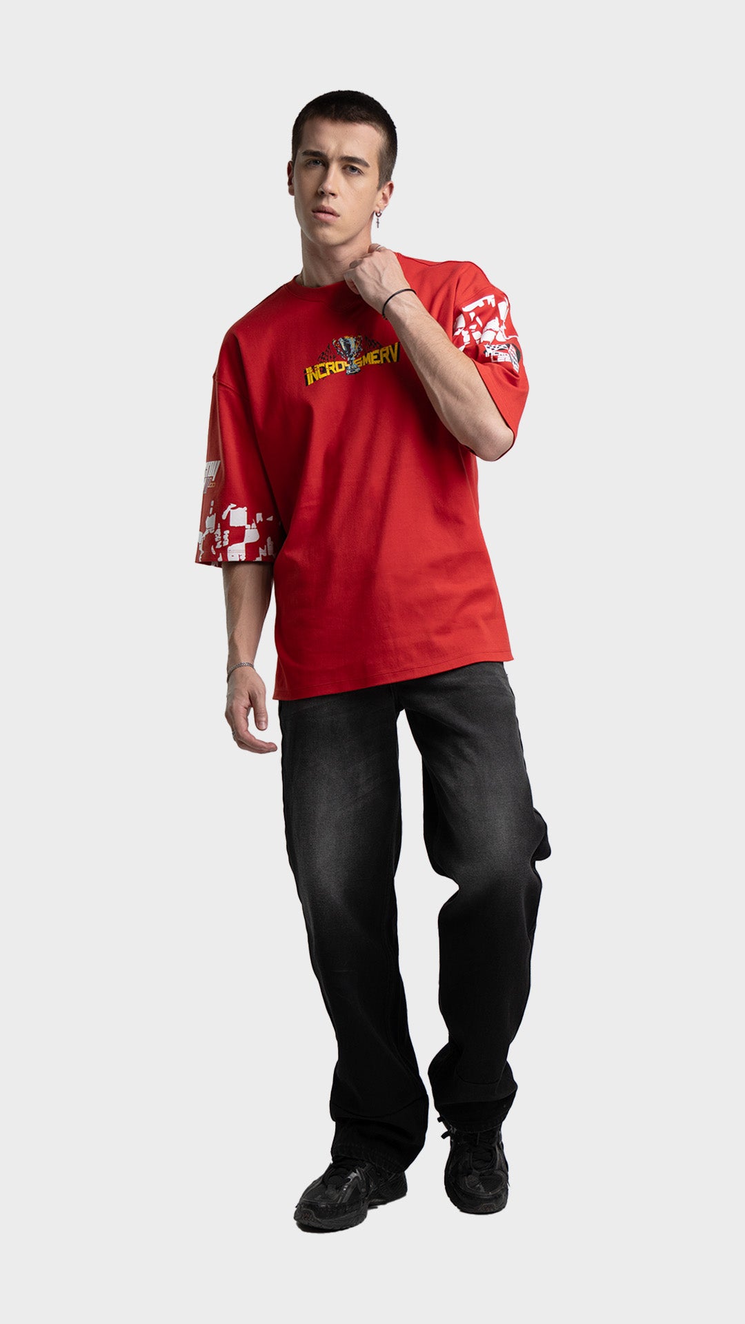 Red racing graphic tee outfit for men. Loose fit drop-shoulder streetwear t-shirt styled with baggy black pants.