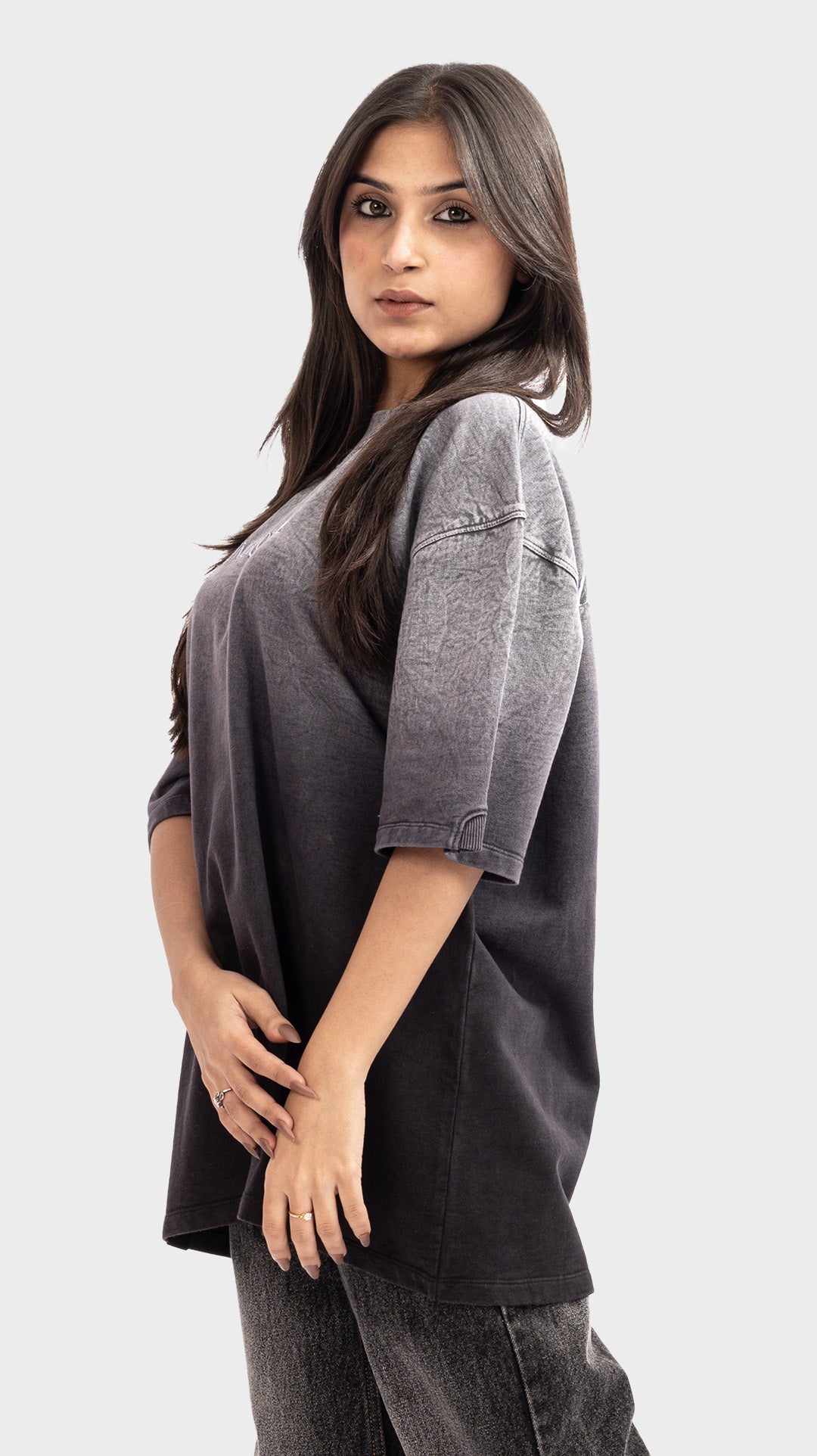 Side profile of a woman wearing a vintage wash grey to black gradient oversized tee.