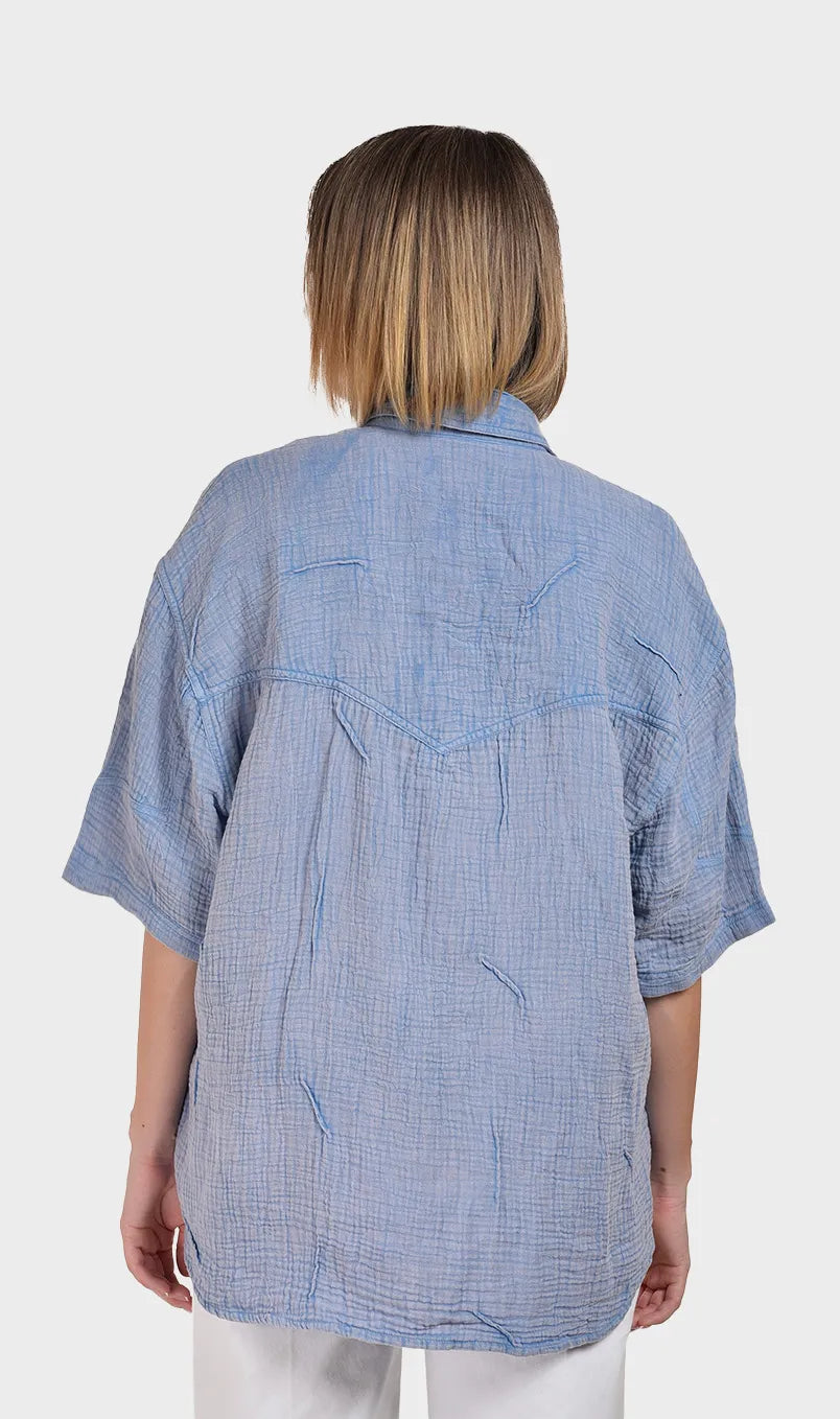 Direct back view showing the relaxed, comfortable fit and textured back yoke of a women's blue 100% cotton double cloth short-sleeve shirt.