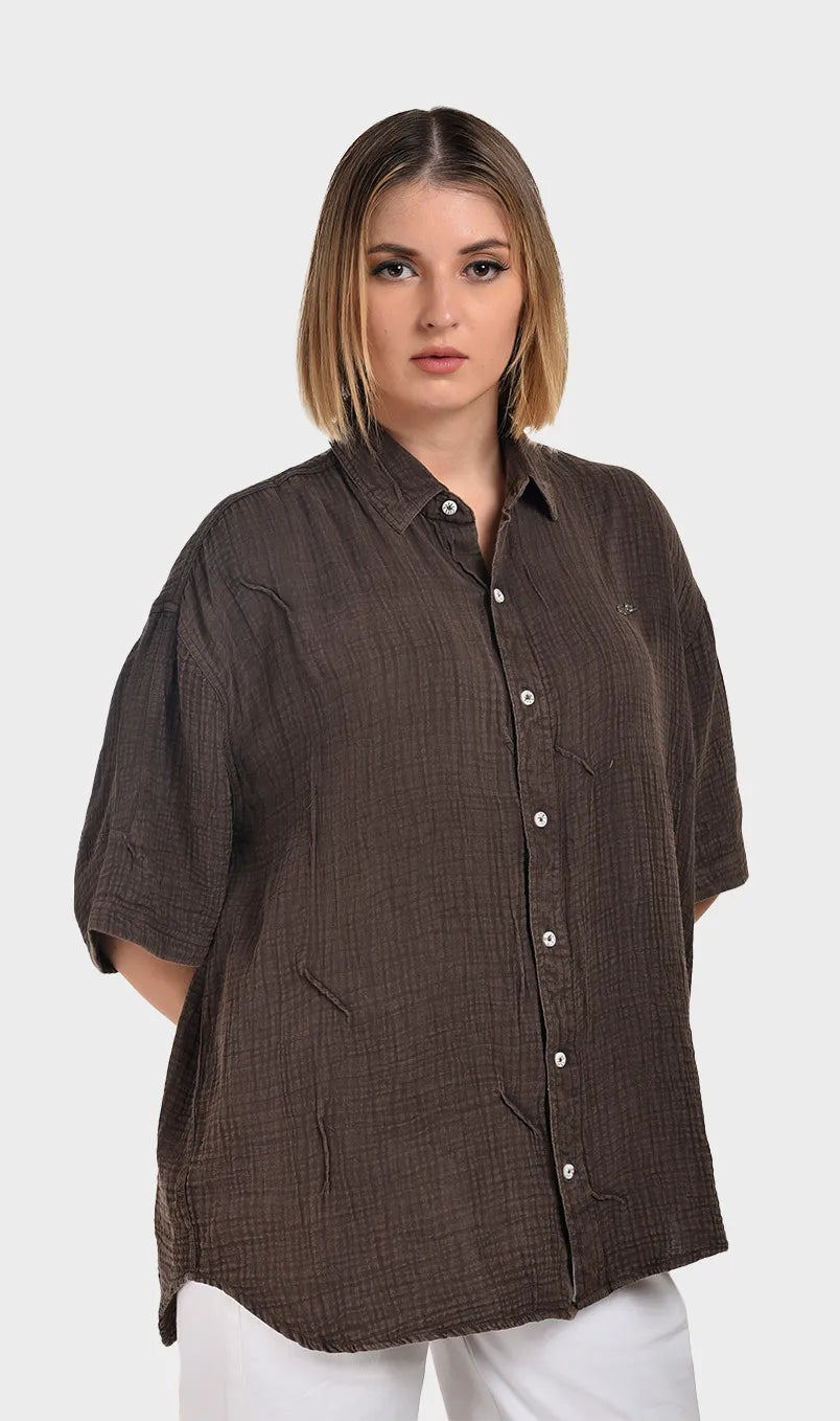 Three-quarter right side view of a model in a dark brown short-sleeve shirt made from breathable 100% cotton double cloth.