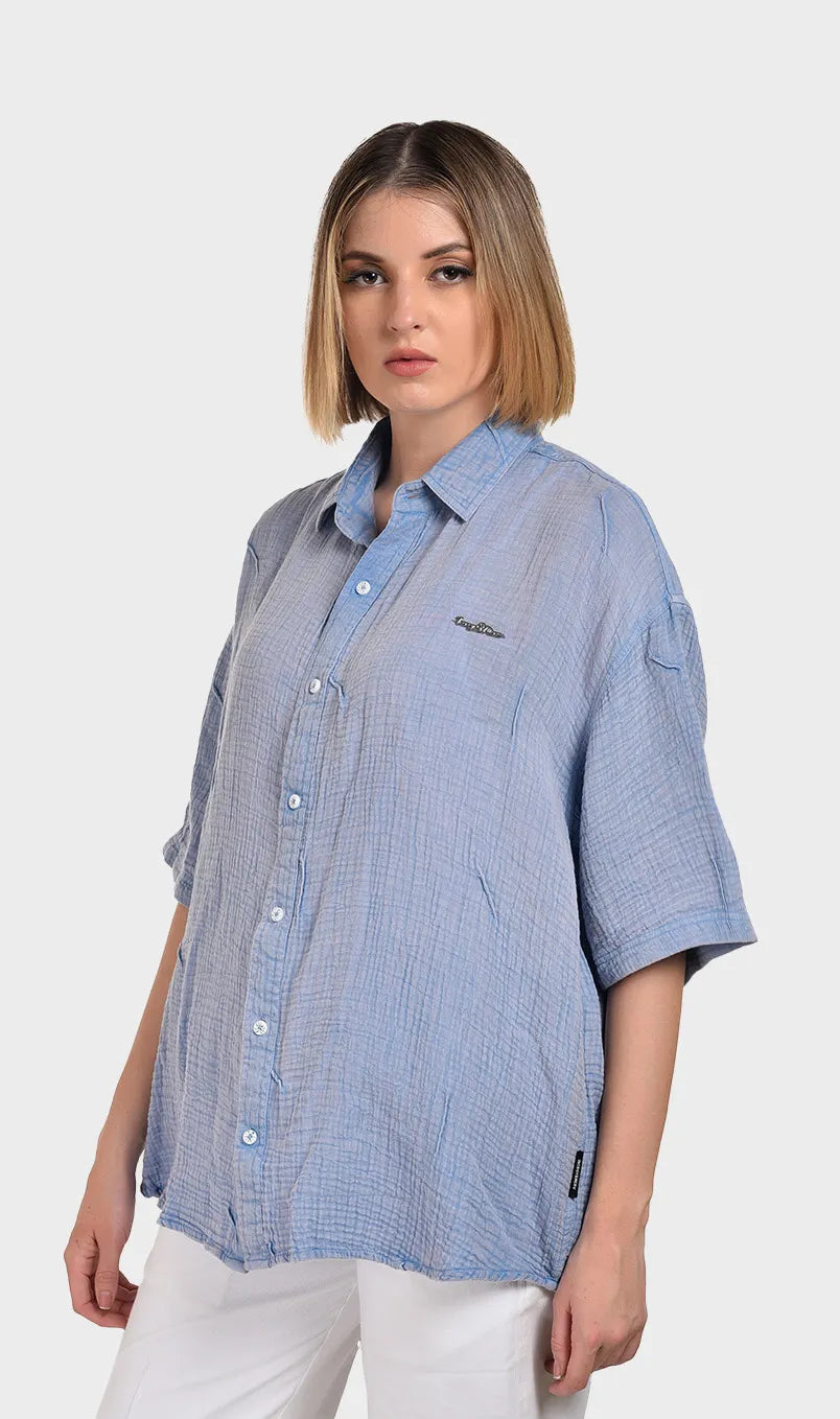 Three-quarter left angle of a model wearing an oversized light blue short-sleeve button-down in breathable 100% cotton double cloth.