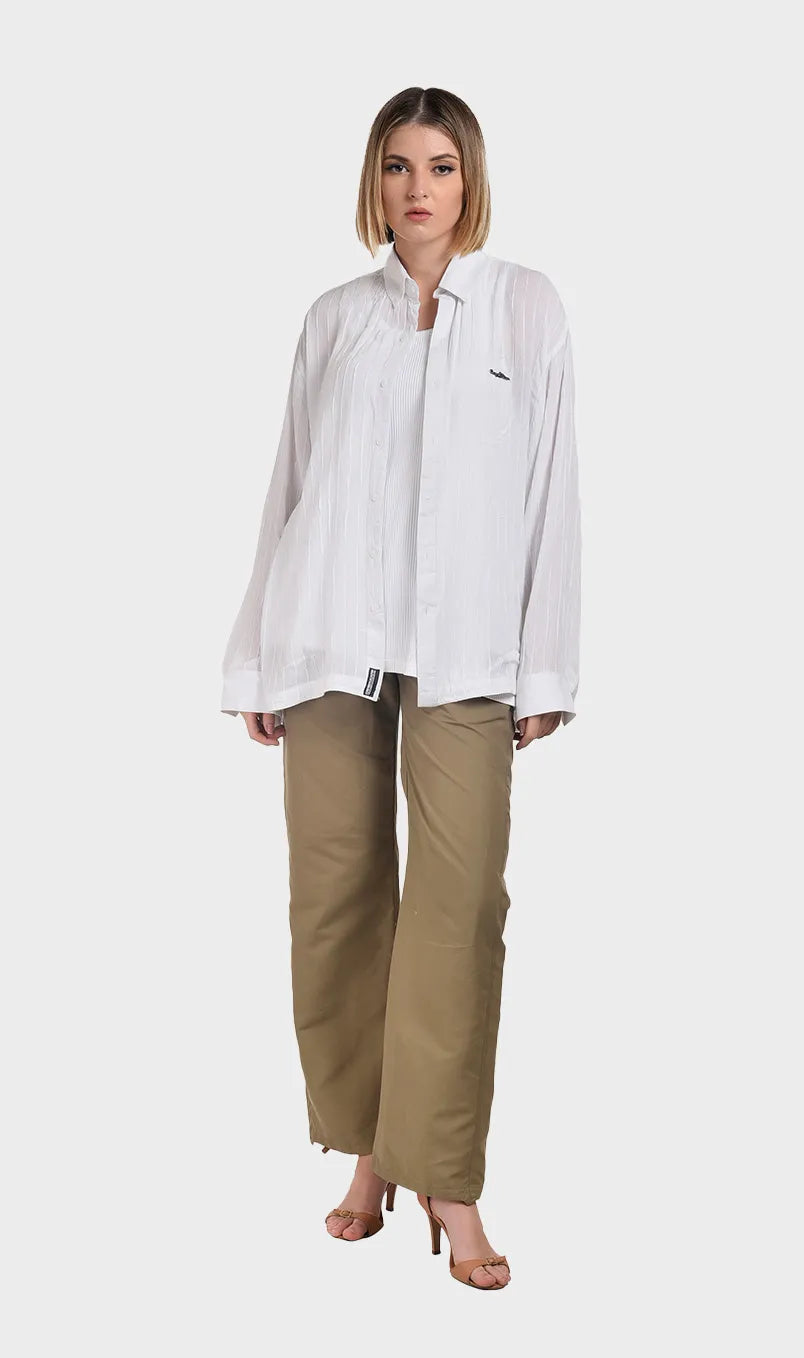 Full-body shot of a model wearing an open white long-sleeve rayon crepe shirt paired with khaki trousers and heels.