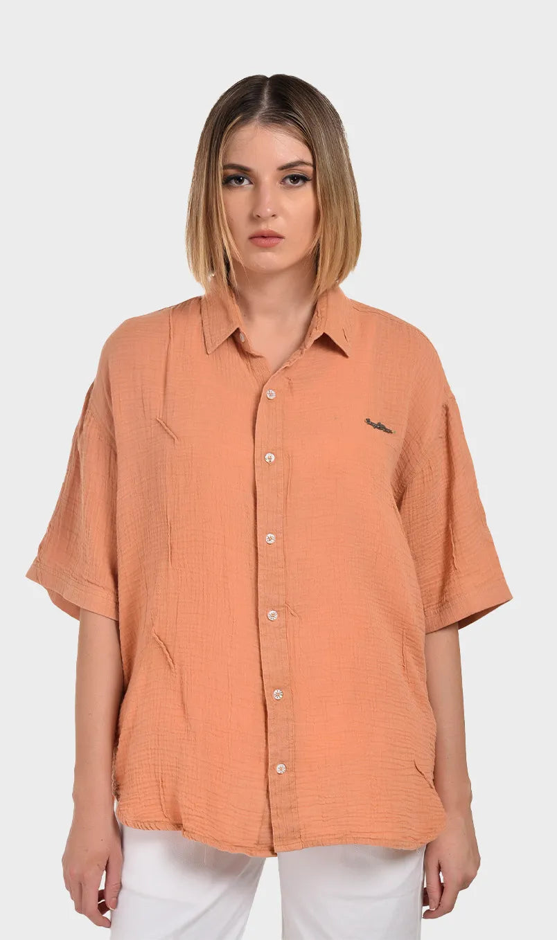 Front view of a women's peach short-sleeve button-down shirt made from textured 100% cotton double cloth fabric.