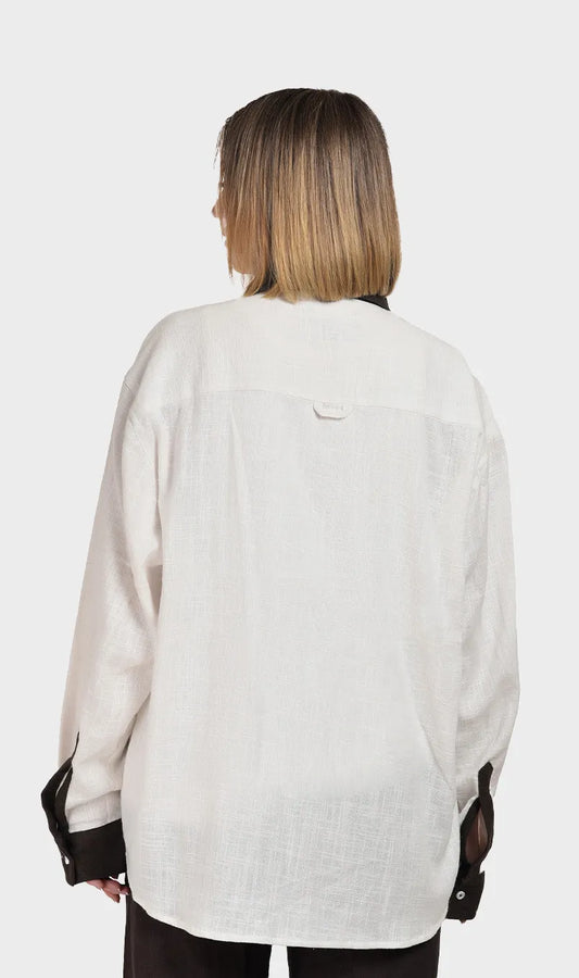 Direct back view showing the subtle slub fabric texture on a women's off-white long-sleeve shirt with brown cuff accents.