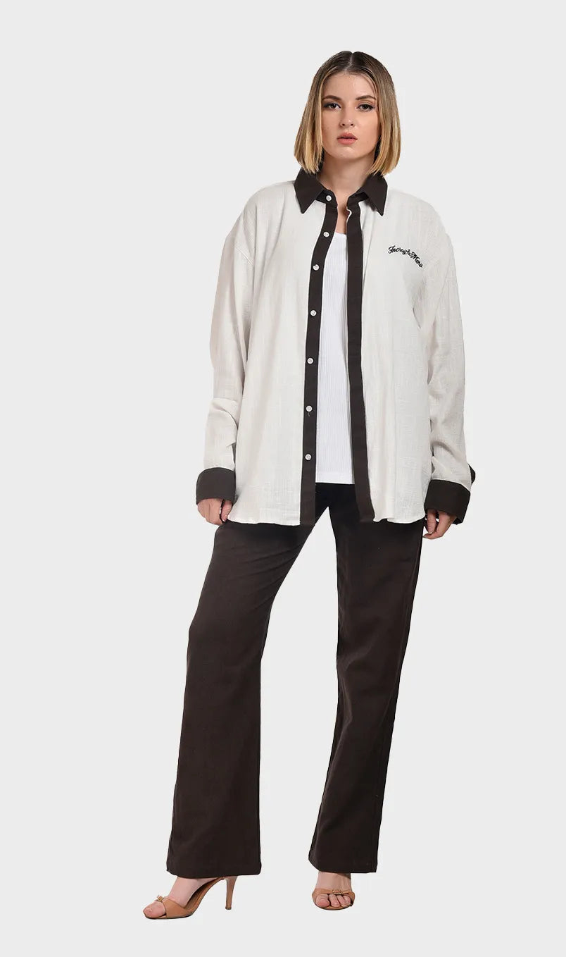 Full-body shot of a model wearing an open off-white slub fabric contrast collar shirt paired with dark brown pants.