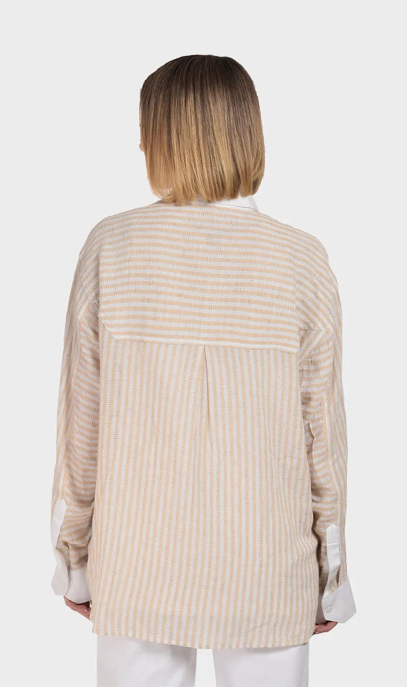 Direct back view showing the relaxed fit, back pleat detail, and horizontal striped yoke on a women's beige dobby fabric long-sleeve shirt.